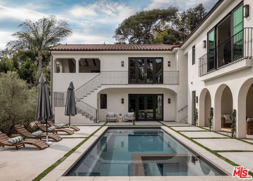 A stunning new contemporary Mediterranean estate perfectly situated in the Hollywood Hills, just moments from Sunset Boulevard and the famed Chateau Marmont. Encompassing approximately 5,800 square feet, this five bedroom, seven-bath residence blends timeless sophistication with modern luxury, highlighted by vaulted wood-beam ceilings, curated natural finishes and expansive walls of glass. The interiors flow effortlessly from elegant living spaces to serene outdoor retreats, including a covered terrace with fireplace framing lush canyon views. A gourmet kitchen featuring a La Cornue French range, Aresbescato marble countertops, and hand-worked bronze Waterworks fixtures flows into a bright breakfast nook with serene tree lined views.  Each en-suite bedroom opens to a private terrace garden surrounded by lush grounds leading to a dramatic pool and spacious covered cabana. A sweeping motor court of hand-laid stone sets a dramatic tone from the moment you arrive, combining generous parking with the grandeur of a true estate approach. The detached ADU offers a private retreat with lush greenbelt views, complete with custom cabinetry, tailored finishes and abundant natural light - ideal for guests, extended stays, or creative use. Additional highlights of the main residence include a graceful spiral staircase descending to a distinctive lower-level landing area, a private home office with bespoke wood shelving, and a luxury screening room designed for an immersive cinematic experience.