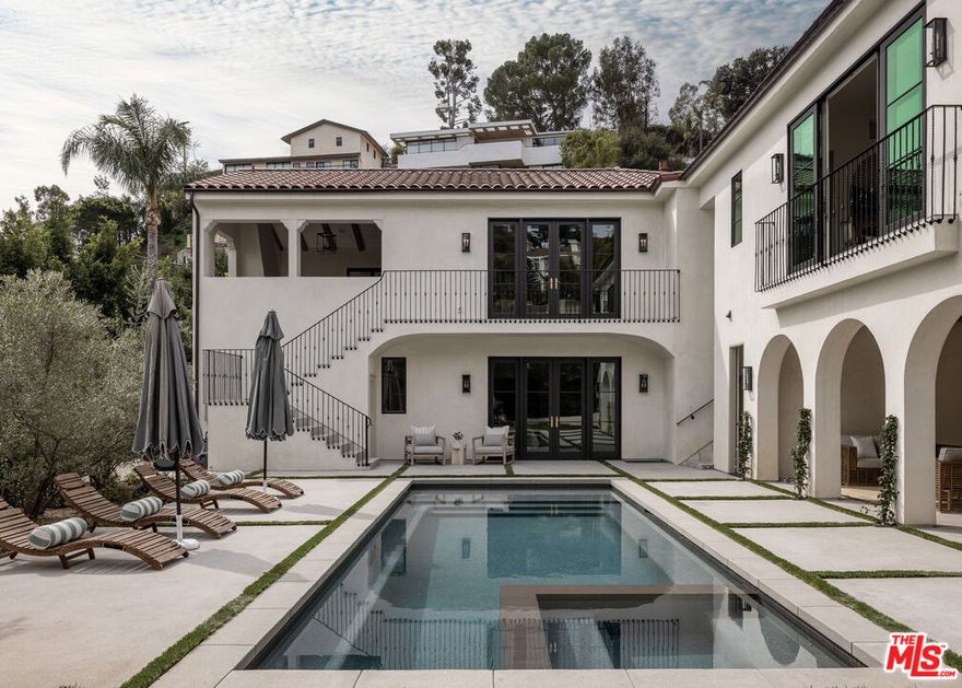 A stunning new contemporary Mediterranean estate perfectly situated in the Hollywood Hills, just moments from Sunset Boulevard and the famed Chateau Marmont. Encompassing approximately 5,800 square feet, this five bedroom, seven-bath residence blends timeless sophistication with modern luxury, highlighted by vaulted wood-beam ceilings, curated natural finishes and expansive walls of glass. The interiors flow effortlessly from elegant living spaces to serene outdoor retreats, including a covered terrace with fireplace framing lush canyon views. A gourmet kitchen featuring a La Cornue French range, Aresbescato marble countertops, and hand-worked bronze Waterworks fixtures flows into a bright breakfast nook with serene tree lined views.  Each en-suite bedroom opens to a private terrace garden surrounded by lush grounds leading to a dramatic pool and spacious covered cabana. A sweeping motor court of hand-laid stone sets a dramatic tone from the moment you arrive, combining generous parking with the grandeur of a true estate approach. The detached ADU offers a private retreat with lush greenbelt views, complete with custom cabinetry, tailored finishes and abundant natural light - ideal for guests, extended stays, or creative use. Additional highlights of the main residence include a graceful spiral staircase descending to a distinctive lower-level landing area, a private home office with bespoke wood shelving, and a luxury screening room designed for an immersive cinematic experience.