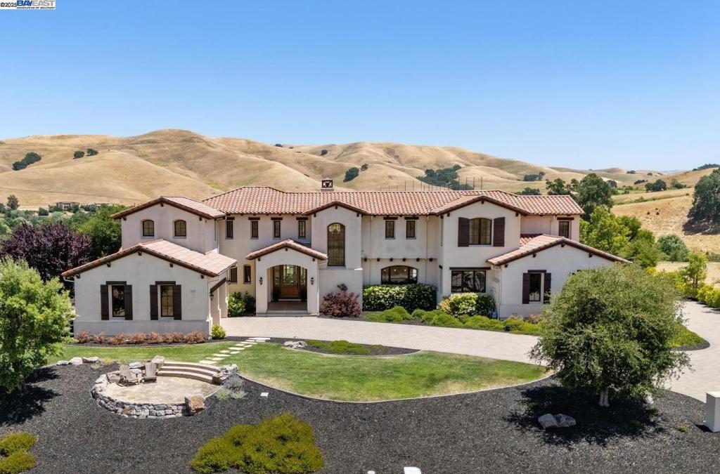 THIS IS IT! Timeless elegance and designer finishes grace this fabulous Mission style custom home surrounded by hundreds of acres of golf course, open space, and oak-studded hills with incredible views. The open floor plan is perfect for modern living, and features 4 bedroom suites, formal office, game room, utility office, and loggia with fireplace. Enjoy soaring vaulted and beam ceilings, distressed hardwood flooring French doors, custom lighting, designer carpeting, arched doorways, skylights, and more. The state-of-the-art granite kitchen is every chef’s dream, with huge center island and walk-in pantry. The expansive great room features a fireplace and wine bar, and the adjacent game room is ideal for entertaining. The primary suite features a spa-like bath with walk-in shower and soaking tub, along with an adjacent viewing balcony with fireplace to enjoy the spectacular views. There is a 4-car split garage, expansive stamped concrete patio, sun deck, garden area, and more. It also has owned solar to keep utility bills low. The expansive private .83 acre cul-de-sac lot offers a enchanted setting which feels like a world away, yet is close to schools, shopping, parks, and walking trails, with easy access to i-680 and the ACE train.
