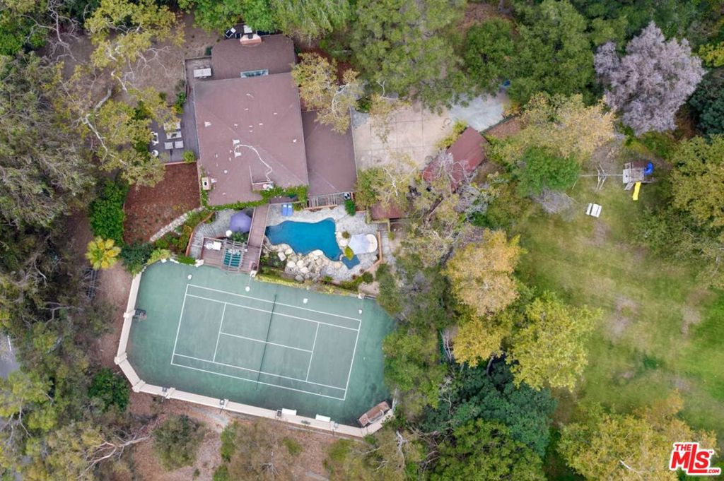 This magical, roughly 1-3/4 acre property is located on Evans Road, a private, country lane bounded on one side by Will Rogers Historic Park (and its famous polo field) and Rustic Canyon Creek (a year-round waterway with natural waterfalls which runs to the Pacific Ocean) on the other. The meandering one-half mile lane, dotted with bridges criss-crossing the creek to the 16 homes located on it, has long been a little-known community, home to globally-known politicians, actors, and industry leaders. Zoned for horses, it's common to see one trotting down the lane and up the trail to the Park and the miles of equestrian and hiking trails beyond. An abundance of towering Sycamores, Eucalyptus and Oak trees conveys a park-like quality and ensures the ultimate in privacy. Maintain the charming remodeled 4,100+ SF, 5-bedroom home, complete with pool and N/S facing tennis court or design the estate compound of your dreams. Crest Real Estate Report and preliminary programming and design by world-renowned architects Woods + Dangaran are available.