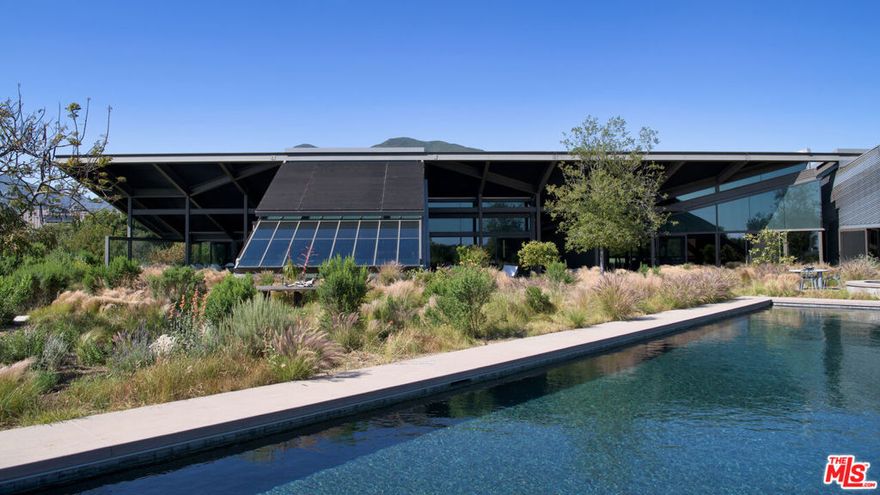 Set on a plateau above Bonsall Canyon in Malibu, this extraordinary property offers an abundance of natural light and captures stunning mountain and ocean views. Spanning four level acres, the estate epitomizes the art of modern architecture and design. Conceived by visionary architect Ed Niles, FAIA, this iconic residence is a striking example of architectural innovation. Surrounded by breathtaking vistas of mountains, canyons, and the shimmering Pacific Ocean, the property offers complete seclusion, accessible via dual gated entries for a truly private retreat. Unlike conventional coastal designs, this 7,200-square-foot masterpiece seamlessly blends concrete, steel, and expansive glass walls in a unique structure crowned by a dramatic wing-shaped butterfly roof. This bold architectural statement not only makes a striking visual impression but also integrates the residence harmoniously with its lush surroundings. Additionally, 1,500 square feet of cantilevered stone terraces enhance the indoor-outdoor flow, providing captivating viewpoints from every angle. The home's sophisticated interiors are a celebration of refined tranquility. Italian marble floors, custom hand-painted pillars, and a subtle coastal palette complement the abundant natural light, creating an atmosphere that is both serene and inviting. Six distinct wings extend from a central hall, each offering a unique character and relationship to the surrounding landscape. From the soaring living room and peaceful study in one wing to the open great room with a gourmet kitchen, dining area, and family room, the layout encourages both intimate gatherings and grand entertaining. Floor-to-ceiling glass walls throughout the home provide sweeping views of the infinity pool, surrounding gardens, and the rugged Malibu landscape, ensuring that every space is bathed in natural light. The primary suite, located in a private wing, features an opulent spa-inspired bathroom with a glass-enclosed shower, an Italian marble soaking tub, and spacious custom closets. Four additional bedrooms, each with remarkable views, offer luxurious accommodations for guests or family members. Designed for sophisticated outdoor living, the estate features a shimmering swimming pool, spa, and a fully equipped outdoor kitchen and BBQ area. A shaded dining pavilion offers the perfect setting for alfresco dining, while professional equestrian facilities complete with a 4-stall barn, a professional jumping arena, and ample pastures provide an unparalleled equestrian lifestyle. The property offers direct access to over 400 miles of scenic riding, hiking, and biking trails, or simply a short golf cart ride to Malibu's pristine beaches.With approved plans for two additional guest structures, this estate is a rare offering, embodying Malibu's spirit of architectural ingenuity, elegance, and natural beauty. This is more than just a home; it's a serene sanctuary and a landmark of modernist design in one of Southern California's most desirable settings.