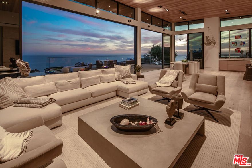 Welcome to 3881 Puerco Canyon Road, a residence that epitomizes the pinnacle of modern luxury living in the coveted enclave of Malibu. A private gated driveway ushers you into this architectural masterpiece, a testament to meticulous craftsmanship and an unwavering commitment to excellence. Upon entry, there is an abundance of natural light that gracefully permeates through floor-to-ceiling windows fully opening to unveil spectacular sweeping ocean views from Point Dume to Santa Monica city lights. This smart home is a sanctuary of modernity, enhanced by fingerprint entry, Control4 automation system with built-in surround speakers, and is beautifully furnished by Restoration Hardware. The heart of this home is the open-concept kitchen, a haven for culinary enthusiasts with top-tier Miele appliances and generous countertop space. The kitchen opens to the dining, living room, and gorgeous ocean-view pool, spa and BBQ/entertainment area. The home includes five bedrooms that are strategically dispersed throughout the expansive floorplan. The primary suite is a true retreat, featuring a chic fireplace, a walk-in closet, and an ensuite bathroom with honed Carrara slab marble walls. Private patios grace two of the bedrooms, while all baths are adorned with Dornbracht fixtures, embodying the essence of refined luxury. The exterior spaces include expansive ocean-view patios, an infinity pool, spa, a well-appointed outdoor BBQ area, three fire pits, and a small putting green. All outdoor spaces were thoughtfully curated, and the spaces were maximized while minimizing grounds maintenance. Completing this coastal masterpiece is an attached 4-car garage, ensuring both convenience and security. Seize the opportunity to experience this combination of modern perfection in one of the most beautiful backdrops on earth.