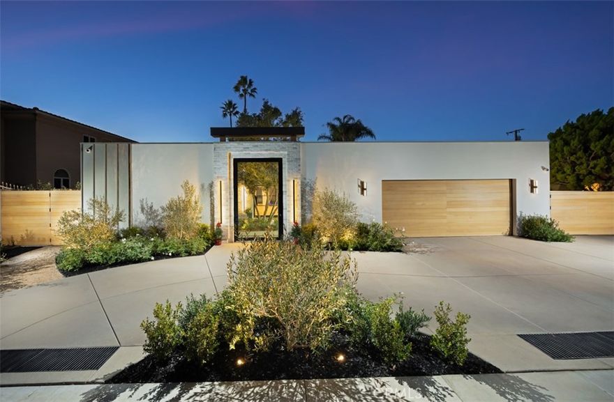 A work of modern art, 1717 Irvine Avenue emerges as a contemporary haven where architecture, nature, and luxury coexist in perfect harmony. Newly reconstructed with uncompromising craftsmanship and a bold artistic sensibility, this residence transcends traditional living. A monumental 10-foot glass pivot door introduces the home with a dramatic reveal: indoor and outdoor spaces collapse into one fluid environment shaped by elemental beauty. A waterfall wall, lush living plant installations, and a mature olive tree bring nature into the core of the home, creating an ethereal threshold that feels both tranquil and unforgettable. Inside, a sweeping open floor plan grounds the home’s modern aesthetic. The living room, wrapped in disappearing glass walls, blurs the boundaries between inside and out and flows seamlessly into the gourmet kitchen. Here, custom cabinetry, a hidden walk-in pantry, striking stone surfaces, and top-tier Thermador appliances elevate the space into a functional work of art, anchored by an oversized waterfall quartzite island. The formal dining room glows beneath a statement chandelier and is framed by dual Thermador 92-bottle wine towers—an exquisite stage for intimate dinners or grand celebrations. The entertainer’s backyard extends the modern narrative with a saltwater pool and spa illuminated by micro-LED lighting, a fully realized outdoor kitchen and BBQ, and generous lounge areas. Whether in sunlight or beneath the glow of the evening lights, the outdoor environment evokes the serenity of a private resort. The primary suite serves as a luxurious retreat—beautifully composed with a sculptural soaking tub, glass-enclosed shower, dual vanities, and a custom walk-in closet. Three additional guest bedrooms feature bespoke closets and share a spa-level bath, while one of the guest bedrooms with custom built-ins can serve as an office, which adds elegant utility to the home’s thoughtful layout. Even the garage becomes part of the design narrative, finished at showroom quality with hexagon lighting, custom cabinetry, and designer flooring. Enhanced by premium technology throughout—including Waterstone fixtures, Lutron lighting control, dual-zone HVAC, central audio, and whole-home Wi-Fi expansion—this residence is as intelligent as it is striking. Positioned near the edge of Newport Beach’s treasured Back Bay, 1717 Irvine Avenue is not merely a home but a modern compound of curated luxuries, bold design, and seamless indoor-outdoor living.