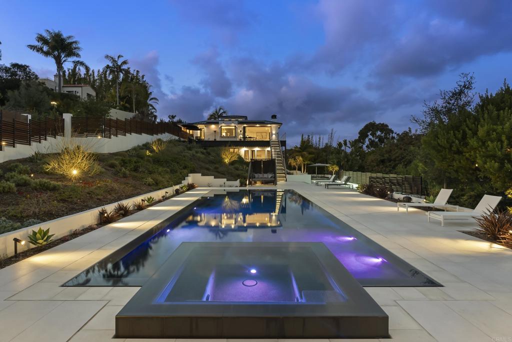 Set behind private gates in Solana Beach, 318 S. Nardo Ave is a stunning modern retreat designed for seamless indoor-outdoor living. Set on a 0.74-acre lot, this fully remodeled 5,408 sq. ft. estate features a main residence, new ADU/Pool house, and expansive outdoor spaces, all embracing panoramic views of the surrounding landscape. The main residence boasts a chefs kitchen with handmade DeVol cabinetry and Gaggenau appliances, an elegant living room with a custom fireplace, and Fleetwood doors that open to outdoor entertaining areas. The primary suite is a private oasis with a spa-like en-suite bath, complemented by five additional bathrooms throughout the home. The newly built ADU/Pool house offers two bedrooms, two bathrooms, a sleek kitchen with Miele appliances, and polished concrete floors, making it perfect for guests or extended stays. Outside, a 50-foot rim-flow pool and spa, Bocce court, fire pit, and multiple seating areas create an entertainers paradise. The home is equipped with ample parking, a security system, and solar panels for energy efficiency. Just minutes from Solana Beach's pristine coastline, Cedros Design District, top dining, and easy freeway access, this exceptional property offers the ultimate in coastal luxury and convenience.