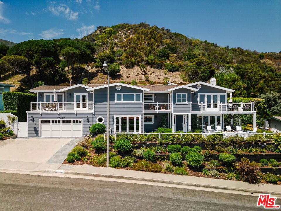 Ideally located in the coveted Pacific View Estates, this exceptional Cape Cod-style, 5-bedroom residence is a perfect blend of elegant design and breathtaking vistas. The captivating ocean views stretch from the Queen's Necklace to Catalina Island and the distant horizon, offering a picturesque setting that defines coastal living at its finest! The elegant front yard, with seating/dining areas and a fire-pit, leads to a two-story entry accentuated by the interplay of space and natural light. The inviting living room, with fireplace and stylish bar, extends to both the front and back yards, creating a harmonious integration of indoor and outdoor spaces. Past the open dining room, the chef's kitchen presents a true culinary haven. Anchored by a spacious center island with a breakfast bar and abundant storage, the kitchen showcases the pinnacle of culinary innovation with top-tier Miele, Viking, and Thermador appliances, including a 6-burner range, double ovens, dual refrigerators/freezers, and a separate wine fridge. The adjacent informal dining area and the spacious family room, both with a profusion of natural light, flow seamlessly to the outdoors, facilitating endless entertaining possibilities. The upper level contains all five bedrooms, including the sanctuary-like primary suite with sublime ocean views, a spacious walk-in closet, cozy office, and a serene bathroom retreat, offering an oversized shower, spa tub and dual vanities. Rounding out the suite is the private deck, capturing the panoramic vistas, with access to the lush grounds by means of a spiral staircase. Down the hallway are four bedrooms consisting of two suites and two bedrooms with a shared bathroom, which are utilized as an office and a gym. The laundry room is also conveniently located on this level. The magical rear outdoor space features an enticing fire-pit/lounge, spa, outdoor kitchen/barbecue, alfresco dining beneath a charming trellis with heaters, and attractive pathways leading up the landscaped hillside slope to mesmerizing, over-the-rooftop views. This remarkable residence offers an additional array of desirable features, including exquisite millwork, attractive wood floors, an outdoor shower, water-softener system, surround-sound Sonos system, whole-house generator, three-zone HVAC system and a finished, two-car garage with ample storage. Don't miss this rare opportunity to experience a unique level of coastal living in this truly impressive Pacific Palisades home!