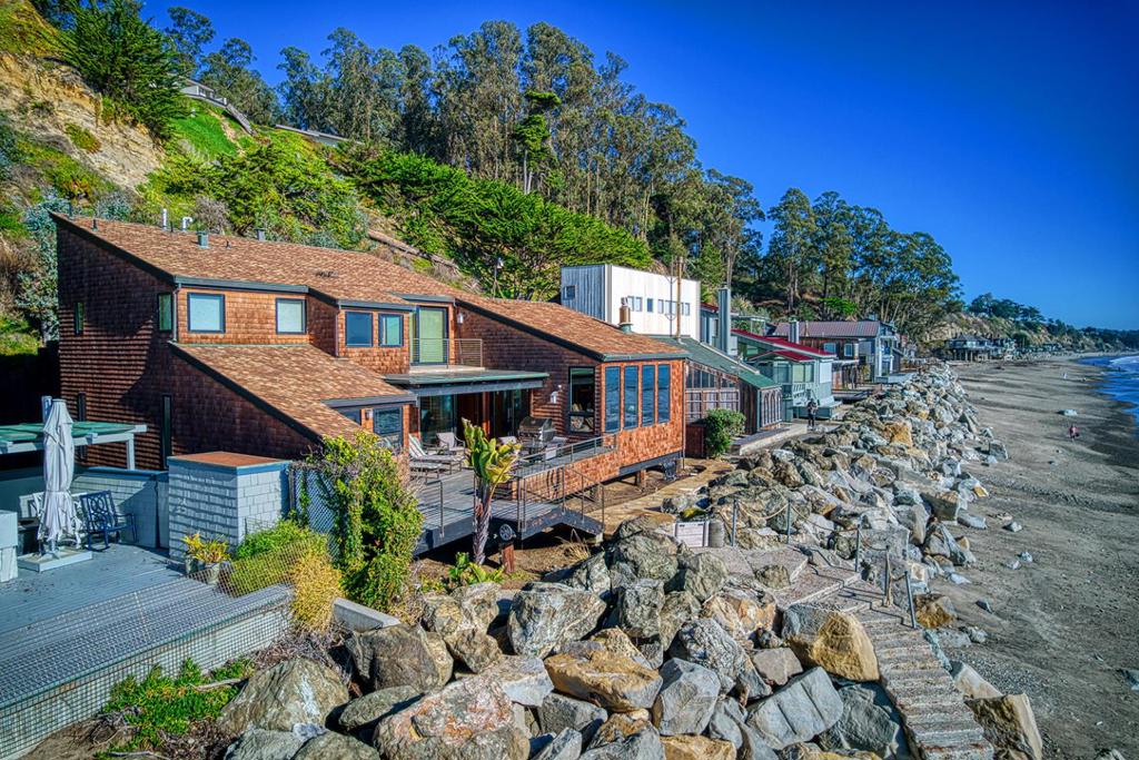 On the sand and beautiful Monterey Bay. A private, gated driveway leads to the homes on Potbelly Beach. Launch the kayak and watch the sea life from this delightful home. Here is your ocean sanctuary. The views span east to west. The windows in the living room frame the ocean. There are large sliding doors from the living and dining rooms open to the deck above the beach, with the perfect indoor-outdoor living. Great open flow for entertaining. Numerous updates include lovely mahogany paneled walls, tile floors, wonderful built in dressers and storage, radiant heat, and custom windows and doors. There are two en suites. The primary bedroom has a balcony looking to the sunset. All the bedrooms have their own unique vistas. You are close to all the amenities of Aptos and Capitola. An easy commute location. Here is a place to retreat, to play and enjoy life on the bay.