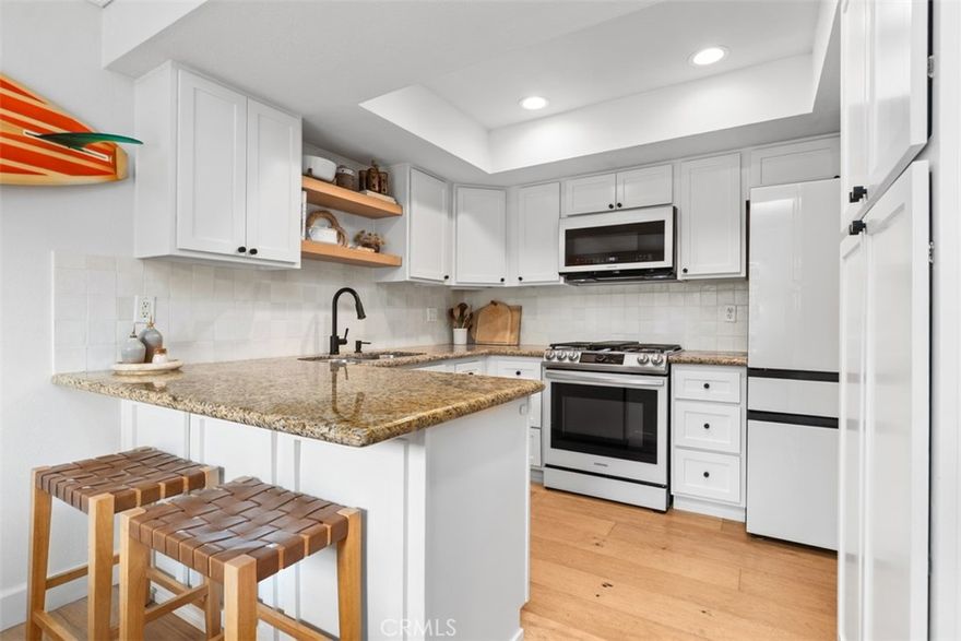 214 Via Robina #5 presents a stylishly renovated condo in the hills of San Clemente with inviting indoor spaces and relaxing views from the upgraded floating floor deck. Two bedrooms, two bathrooms and one car garage located on large cul-de-sac.

The showpiece kitchen features modern Shaker cabinetry with CB2 matte black hardware, a handmade Zellige Moroccan tile backsplash with tight grout lines for sheer beauty, and granite countertops with a deep double sink. A suite of Samsung Bespoke matte black appliances, accented with white glass fronts, includes a five-burner gas range with oven, coordinating refrigerator, microwave and dishwasher. A raised ceiling with recessed lighting and an adjacent built-in banquette with custom cushions create a warm, functional dining space ideal for gatherings of up to 10–12.

Both bathrooms have been elevated with designer mirrors, the primary featuring timeless marble flooring and the hall bathroom showcasing large-format porcelain floors and custom shelving.

Throughout the home, brushed European oak engineered wood floors, finished with polyurethane for durability and beauty, add richness. Additional details include 4-inch crown molding, six-panel doors, and textured cut-pile carpet in the bedrooms. Each bedroom also offers a matte black ceiling fan for style and comfort.

Other highlights include a central heater (installed 2016), dual-pane windows, custom built-in Shaker-style entertainment cabinetry in the living room, and a full-size stacked washer/dryer. For leasure enjoy the HOA common area garden for residents and common area patio with coastal and ocean views!

This thoughtfully upgraded residence combines craftsmanship, comfort, and design — all within minutes of San Clemente’s beaches, shops, and restaurants.