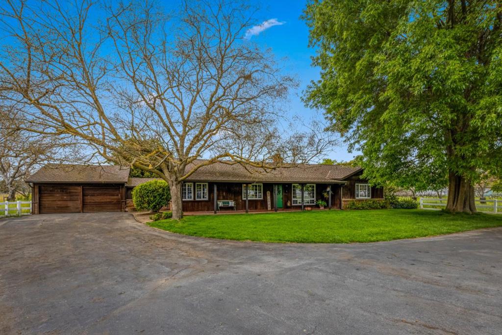 Embrace the lifestyle you've always dreamed of in this charming 3-bedroom, 2-bathroom ranch home in the heart of San Martin. With over 4 acres of land, the possibilities are endless! A picturesque, expansive front yard is framed by beautiful vinyl split-rail fencing, creating an inviting, serene atmosphere. Inside, the updated kitchen features a commercial-style freestanding range and hood, perfect for the home chef. Fresh interior paint and new carpeting throughout, complemented by elegant crown molding, create a polished and cozy feel. The living room's fireplace insert adds warmth and charm. A breezeway connects to the detached garage, while a screened-in room allows you to savor the beauty of country evenings. The property also boasts a mature walnut grove, offering both beauty and potential. Additionally, a separate auxilary living structure and driveway (status of permits not known and agent/buyers to advised to investigate with the county). Dont miss out on this perfect blend of comfort, style, and space!