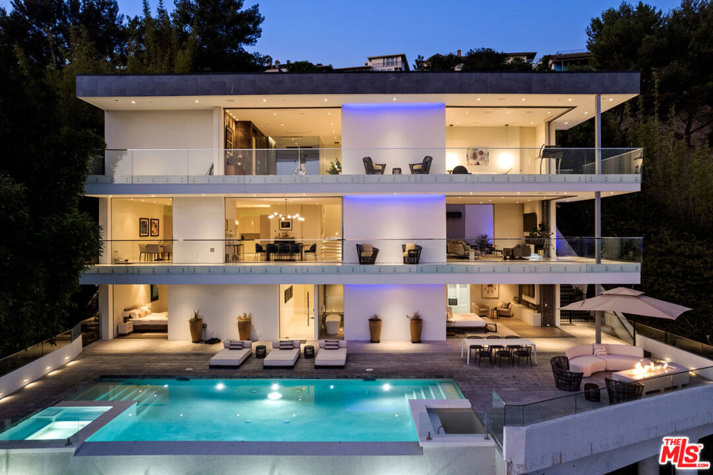 Set at the end of a private, gated drive, this architectural masterpiece offers unparalleled privacy and sweeping panoramic views stretching from Downtown LA to Catalina Island. Featuring three levels of seamless indoor-outdoor living, the home boasts polished white marble floors, floor-to-ceiling glass walls, and stunning vistas from every room. The first level includes a spacious lounge and luxurious bedroom suite. A floating staircase leads to the second level, where a chef's kitchen with high end appliances, custom European cabinetry, indoor/outdoor dining areas, and a private guest suite await. The lower level is a true retreat with two additional bedrooms, including a master suite with direct access to a resort-style infinity pool and swim-up bar. Expansive patios, lounging areas, and a cozy fireplace complete this extraordinary home, designed to captivate and elevate your lifestyle.