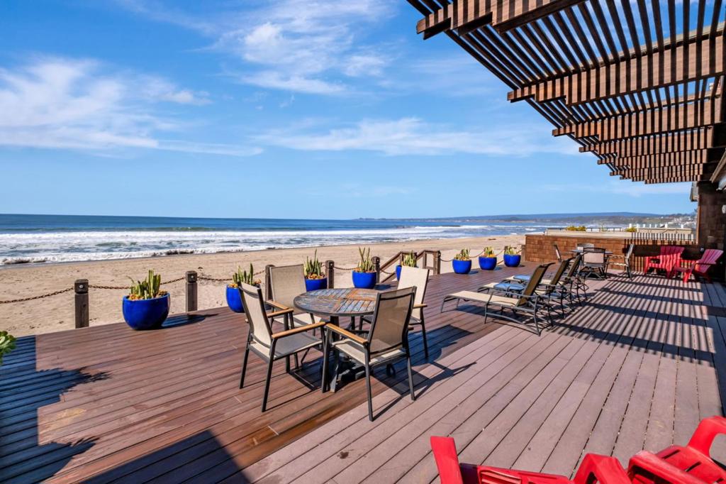 discover your dream coastal escape in this stunning 4+ bedroom 4 bath beach front home on coveted beach drive. This beautifully designed residence seamlessly blends warm, natural wood interiors with breathtaking panoramic ocean views, Features include 50x20 foot ocean front deck with only 10 steps down to beach. The open concept living and dining area boast floor to ceiling wood casement sliding glass doors that flood the space with natural light and unobstructed views. Central eye catching copper clad fireplace adds warmth and charm. Multiple outdoor living areas: In addition to the beach front deck enjoy a private rooftop terrace and a secluded courtyard with access to all first level bedrooms. Special features: Security gates, shutters on the ocean side, retractable remote operated patio screens, New laminate floors on first level. Amazing six gables roofline that creates a dramatic effect especially at night as the recess lighting gives a soft warm glow off the clear heart wood interior ceiling and walls. Separate in law suite with loft that can be used as a sitting area, office or extra sleeping. House has been rented as a vacation rental earning $10,000 per week