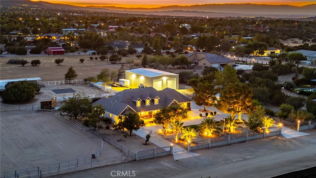 A rare opportunity to own a private, custom-built equestrian retreat with sweeping mountain views, a massive permitted workshop, and endless upgrades—all on 2.5 acres of land! Nestled behind a block and wrought iron fence with electric gates, this stunning estate boasts curb appeal with professional desert landscaping, mature palm trees, a rose garden, and a spacious U-shaped driveway with full RV access. Inside, you’ll find soaring ceilings, wood-look plank flooring, upgraded baseboards, plantation shutters, and energy-efficient LED lighting. The formal living room features a cozy fireplace with custom mantle and built-ins, while the dining room offers a mini bar with a wine fridge and beverage cooler. The remodeled chef’s kitchen stuns with custom Knotty Alder cabinetry, live-edge stone countertops, rustic pendant lighting, tile backsplash, stainless steel appliances, and a premium 6-burner Dacor range. The downstairs primary suite is a luxurious retreat, featuring travertine floors, crown molding, a spa-like bath with dual vanities, a clawfoot soaking tub, and a stone-tiled shower with rain head and body sprays. The adjacent walk-in closet spans an entire room, complete with high-end built-ins. A stylish laundry room offers live-edge counters, a deep utility sink, and ample storage.
Upstairs includes three spacious bedrooms and a full bath. The private backyard oasis is fully enclosed with block walls and features grassy areas, a pergola, firepit, and covered patio—perfect for enjoying the mountain views. The upper portion of the property is built for equestrian lovers with 4 horse corrals (each with water, shade, and misters), a horse wash area, pig and cow pens, a 10’x20’ hay barn, freestanding shelter, riding arena, and a rustic Western-style saloon currently used as a tack room. The 40’x60’ fully permitted workshop includes skylights, 110v/220v power, RV hookups, and dual oversized roll-up doors—perfect for hobbyists or professionals. A mature orchard with plum, peach, apple, almond, and apricot trees completes this exceptional property. Additional features include dual-pane security windows, three mini-split systems, two HVAC units, and two swamp coolers for year-round comfort. Located in the desirable Westside Union School District and just minutes from shopping and dining, this one-of-a-kind estate offers privacy, functionality, and luxury—all in one.