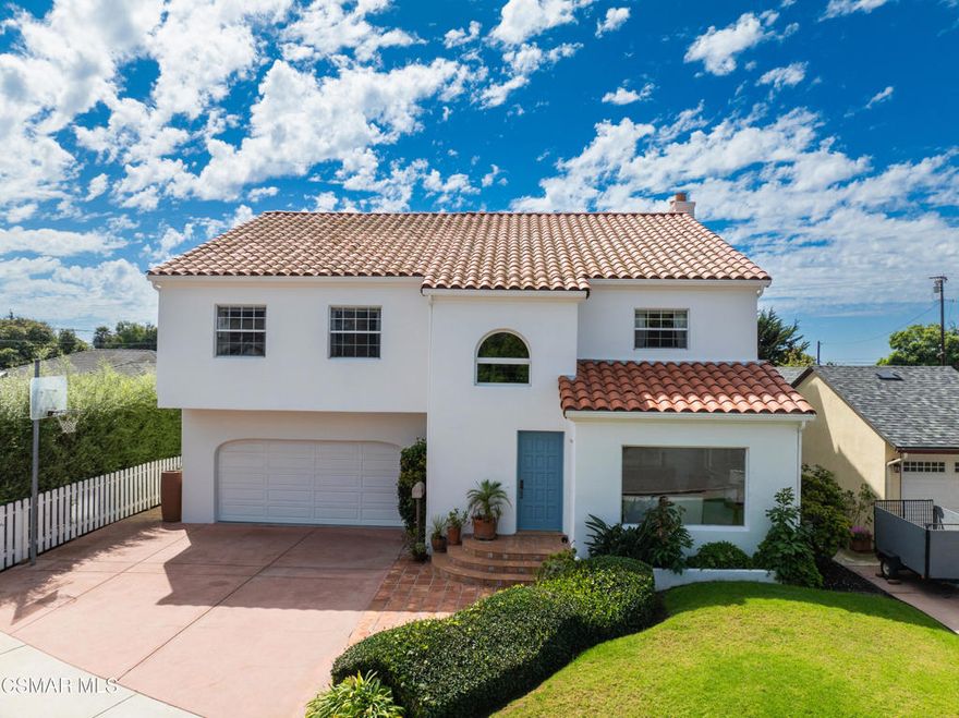 Striking Spanish Revival inspired Ventura coast home, originally built in 1949 and thoughtfully expanded and renovated in the late 1980's. Offering approximately 3,001 square feet across two levels, this residence combines timeless character with modern comforts.  The main floor features a spacious den or office with a full bath, a formal living room with a large picture window, and a generous kitchen designed to gather everyone in the heart of the home. Kitchen highlights include a charming fireplace, commercial grade stove with griddle, ample cabinetry, extensive counter space, and multiple windows and French doors that open to the verdant backyard. With the fire glowing and conversations flowing onto the patio, this kitchen is an entertainer's dream.  A dramatic staircase leads to the upstairs bedrooms, all filled with natural light. Three bedrooms share a well appointed hall bath with dual sinks and a full tub shower. One whimsical bedroom features a loft with a picture window, sparking the imagination. The dramatic primary suite offers soaring ceilings, a massive walk in closet, and a private study or office with its own brick fireplace. Step out onto the balcony and enjoy views of the lush garden below and, on clear days, the sparkling Pacific Ocean. Additional features include a three car tandem garage with cabinetry, an indoor laundry room, and a backyard designed for both beauty and ease of living. Multiple seating areas, a water feature, a gas fire pit, citrus trees, and an easy care deck create a magical outdoor setting. This remarkable property invites you to immerse yourself in coastal living, with the beautiful beach less than a mile away.
