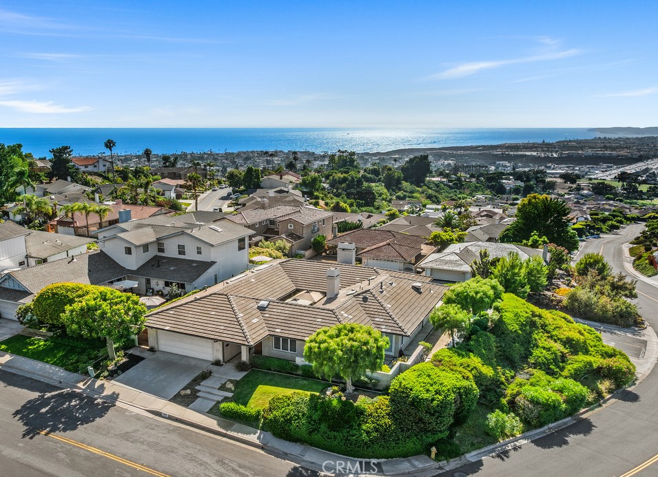 Exquisitely maintained, this home offers numerous refined amenities on a desirable cul-de-sac location with breathtaking ocean, harbor and coastal hill views. A single level showpiece with 2,224 square feet of living space. Step through the custom teak entry gate into your secure and private courtyard, centered around a gas fireplace embraced by custom French doors. Brazilian hardwood floors extend through the adjacent kitchen, guiding you into a sun-filled dining area illuminated by skylights. The countertops are crafted from Caesarstone and are paired beautifully with Starphire glass-faced cabinetry. Enjoy premium appliances from Wolf, Viking, Jennair, and Monogram. The stunning living room showcases Sisal coconut fiber flooring and a vaulted tongue-and-groove ceiling with surround sound. Relax with sit-down ocean and harbor views through the custom Marvin French doors. A herringbone firebox, accented with a single slab of travertine surround, completes the inviting ambiance. The primary bedroom features expansive glass doors opening to ocean breezes and lay-down sunset views. The main bathroom impresses with a spacious walk-in shower, operable skylight, and a deep Japanese style soaking tub offering mountain and ocean views. Thoughtful details abound, from custom made walk in California Closets to Ginger lighting and heated vanity mirrors. The lavatory bidet is Toto and has wall-mounted controls. A guest bedroom with private access offers an ensuite full bathroom, while two additional rooms have been transformed-one into a tranquil Zen like space with custom Japanese meditation bench and French doors facing a peaceful water feature, and the other into an E-savvy library with built-in cabinetry and a workspace designed to de-clutter cords. Step outside to enjoy a game of bocce ball, then unwind in the private recessed Kiva with a gas fire pit. And there's more: Perimeter camera security system, Interior motion sensors, Audio/Visual E closet, Two tankless water heaters, Automated patio awnings, Epoxy garage floors, Ultra-smooth wall surfaces, Light concrete roof tiles, Deep utility garage sink, Recessed lighting and Upgraded electrical panel. An impeccable home - make it yours.