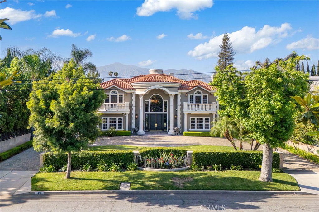 Welcome to an extraordinary estate where elegance and grandeur meet in perfect harmony. Tucked behind a private gated entrance, this architectural masterpiece spans 6,184 square feet on a 19,304-square-foot lot with a coveted south-facing orientation. Every detail reflects refined luxury, offering an unparalleled blend of timeless design and modern sophistication.
Arrive through a fully gated circular driveway with dual entrances, leading to a double-height entry where a gold-leaf staircase spirals beneath an opulent chandelier. Exquisite hardwood floors, gallery-style hallways, and mosaic-tile wall finishes create a seamless blend of artistry and craftsmanship.
The sunken formal living room offers refined comfort, while the formal dining room stuns with its Baxter crystal chandelier, domed ceiling, and custom display shelves. The gourmet kitchen boasts Scavolini custom cabinetry, Miele appliances, and a Caesar stone countertop from Israel. An intimate breakfast nook overlooks the koi pond, lush landscaping, and sparkling pool, while a separate Wok kitchen with Gaggenau appliances is designed for grand-scale entertaining.
The family room soars with a dramatic 28-foot ceiling and towering windows, filling the space with natural light. A mosaic-tile fireplace adds warmth, while the wet bar complete with a Sub-Zero wine cooler and custom cabinetry sets the stage for effortless entertaining. Step outside through French doors, where a sprawling patio offers relaxation and sophistication.
A custom designer office features rich wood-paneled walls and hand-built cabinetry. The state-of-the-art home theater is equipped with immersive surround sound and Crestron automation, offering the ultimate entertainment experience.
Upstairs, four sumptuous bedroom suites provide private retreats. The grand master suite is a sanctuary of luxury, featuring a fireplace, two walk-in closets, and spa-like bath with a jacuzzi tub, glass-enclosed shower, gold-leaf custom vanities, and aqua-glass mosaic accents.
Park-like grounds feature mature trees, cascading waterfalls, and lush privacy-enhancing foliage. Lounge by the resort-style pool and spa, gather around the outdoor fireplace, or stroll through the lavish gardens immersed in serenity.
This isn’t just a home; it’s a statement, an experience, a legacy. Indulge in Southern California’s pinnacle of luxury living and make it yours today.