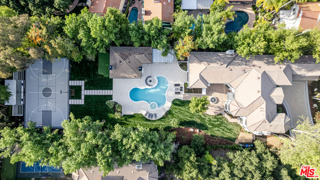 "THE HAVEN" -- An Entertainer's Dream Estate in the Heart of Calabasas. Tucked away at the end of a cul-de-sac in one of most exclusive guard-gated communities of Calabasas, this grand estate is a private sanctuary designed for those who live boldly and entertain lavishly. Set on over one flat acre of lush, secluded grounds, this just-reimagined masterpiece spans 11,257 square feet of unmatched luxury. From the moment you enter, you're greeted by soaring ceilings, expansive sun-filled spaces, and exquisite craftsmanship throughout. White oak hardwood floors, custom marble fireplaces, and designer finishes elevate every room to a gallery-like experience. Curated for the ultimate lifestyle, the estate features two primary suite retreats, a full-court basketball and pickleball court with pavilion lounge, a state-of-the-art theater, glass-enclosed whiskey and wine bar, and a dedicated billiards lounge. Entertain effortlessly in the showstopping gourmet kitchen, host guests fireside in the sunken outdoor fire lounge, or unwind on the putting green under the stars. The resort-style outdoor amenities continue with a sleek bar and kitchen pavilion, manicured grounds, and mature trees offering total privacy and tranquility. The guest home boasts 2 bedrooms with ensuite bathrooms, a full kitchen, and livingroom that doubles as a lavish pool cabana. THE HAVEN is a rare offering of this scale, sophistication, and serene setting. This is more than a home. It's a destination.