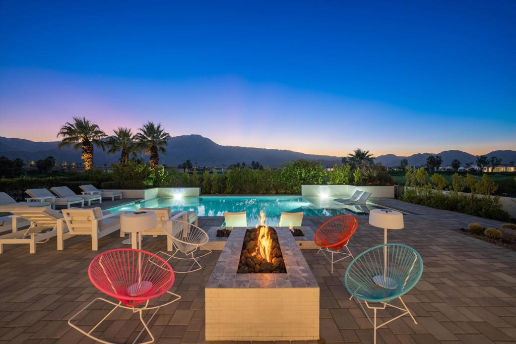 Welcome to an extraordinary architectural masterpiece in the heart of Andalusia at Coral Mountain. With breathtaking views of the Santa Rosa and Coral Mountains, this designer turnkey residence seamlessly blends artistic flair with luxurious living, creating a one-of-a-kind sanctuary. Step inside to discover meticulously crafted details throughout. The great room features a custom marble wall with a linear fireplace, complemented by a custom curved sofa, oversized porcelain tile floors and motorized shades that allow natural light to pour in. Dual kitchen islands with contemporary waterfall edges in Pental Quartz anchor the chef's kitchen, equipped with high-end appliances. The dedicated office is a vibrant and inspiring space, enclosed with French doors and custom built-ins. The home's four bedrooms each tell a story. The primary suite opens to a private terrace and pool, boasting a serene blue mural of sunlit water. A guest casita provides the perfect retreat while the junior suite features a bold tangerine wallpaper and modern accents. Outdoors, a ''palatial'' pool deck invites relaxation with vibrant seating and a fire pit encircled by berry-hued chairs. Lounge poolside, entertain at the outdoor kitchen, or unwind in the raised spa with spillway--all framed by lush landscaping and spectacular golf course views. Offered furnished, every inch of this home has been thoughtfully curated by designer Jeff Valenson to inspire joy and unforgettable memories!