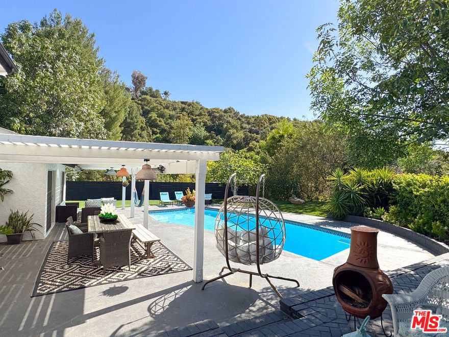 Brimming with character and nestled in the beloved "artist streets" of Woodland Hills - Picasso, Gauguin, Matisse, Da Vinci, and Cezanne  - this beautifully remodeled 5-bedroom, 3-bath + pool home sits at the scenic junction where Topanga Canyon, Calabasas, and Woodland Hills converge. Thoughtfully designed for comfort, connection, and California living, the spacious layout features sun-drenched interiors and a seamless indoor-outdoor flow. A modern minimalist kitchen anchors the heart of the home, complete with a large breakfast island with built-in charging station, sleek hooded range, and stylish lighting. The adjacent dining area leads to both formal and informal sunken living rooms, where newly added French doors open to the landscaped backyard. A corner bar in the family room invites relaxed evenings  whether you're gathering for sunset cocktails or cozying up by the upgraded fireplace (now both wood and gas). With five versatile rooms, the home includes a private guest suite with direct access to a side courtyard and a dedicated office ideal for remote work or creative pursuits. Upstairs, the expansive primary suite offers peaceful pastoral views, a spa-like bath with double-sink vanity, oversized shower, and ample closet space. Two additional spacious bedrooms and two additional full bathrooms round out the interior. Outdoors, the newly landscaped grounds feature lush turf, an extended side yard for play, a heated pool with new filtration system, covered patio, and multiple private nooks perfect for dining, lounging, or unwinding under the stars all set within a privacy-fenced perimeter. Located moments from scenic hiking and biking trails, award-winning schools, and premier shopping, this is more than a house - it's a home base for inspired family living.