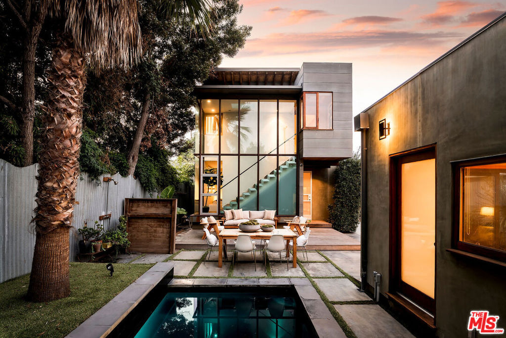 A rare fusion of historic Venice charm and striking modern architecture, this redefined 1922 Craftsman stands as a design-forward masterpiece on one of the best streets in Venice. Completely reimagined with meticulous attention to detail, the residence achieves a seamless balance between soulful warmth and bold contemporary form. The home begins with the inviting scale of a classic Venice bungalow, warm and intimate, before unfolding into dramatic contemporary spaces at the rear. Walls of steel-framed glass dissolve the boundary between indoors and out, while exposed wood and architectural steel details ground the home in authenticity. The open-concept living and dining areas flow into a chef's kitchen defined by charcoal-stained cabinetry with brass hardware, poured concrete countertops, dramatic grey marble backsplash, and a suite of top-tier Sub-Zero and Bertazzoni appliances, a space both functional and artful. The primary suite is a private retreat perched above it all, framed by soaring butterfly ceilings, expressive wood-and-steel joists, and abundant natural light. A custom white oak walk-in closet leads to a spa-worthy bath featuring oak cabinetry, radiant heated concrete floors, Watermark fixtures, and full marble slabs that elevate every detail. Two additional bedrooms and a dramatic family room with double-height ceilings complete the main house, each space thoughtfully oriented to maximize scale and flow. A wall of glass at the back staircase rises floor-to-ceiling, casting the interiors in a constantly shifting glow and connecting seamlessly to the outdoor environment. Outside, the backyard transforms into a true entertainer's stage: a raised dining terrace, lounge seating, lush greenery, and a sleek pool that reflects the architecture like a mirror at dusk. The property also includes a versatile converted garage ADU, complete with accordion glass doors and a full bathroom finished with handcrafted Moroccan Zellige tile. In addition, a temperature-controlled wine room adds a refined architectural touch, combining function with sophistication. Together, these spaces provide unmatched flexibility, ideal as a fourth bedroom, guest suite, private gym or creative studio. Every element of this home reflects intentional design, elevated craftsmanship, and a deep connection to Venice's artistic spirit. It is not just a house, but an architectural statement, a Venice dream, realized.