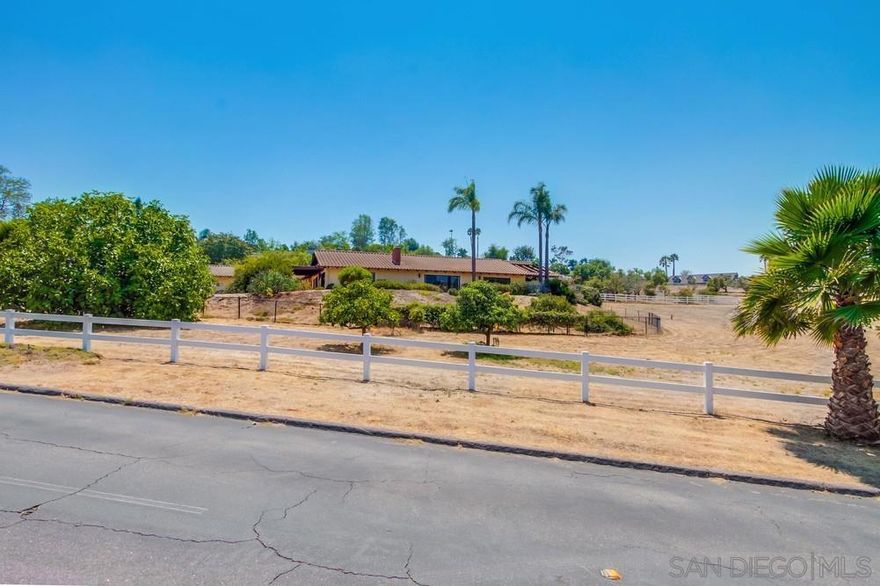 Indulge in panoramic views and breezy coastal weather from this single-level Hialeah Estates home tucked away on a rare, flat 2.6-acre corner lot in the heart of Bonsall’s most established executive neighborhood. This sprawling ranch-style residence offers endless potential with soaring vaulted ceilings, floor-to-ceiling windows, and wood-beamed architecture that brings warmth and character to every oversized room. Beautiful hardwood floors flow throughout, and the spacious great room connects formal and informal living areas—each with its own fireplace. The country-style kitchen opens to a shaded veranda perfect for morning coffee or evening breezes. A charming garden room off the primary suite adds extra space for relaxing or creative pursuits.  This is the lowest priced home in Saratoga by over $500,000—offering an exceptional value for anyone seeking land, space, and opportunity. The massive laundry room includes a sink and abundant cabinetry. A 36-panel solar system offsets energy costs, and the attached 5-car garage makes room for your workshop, toys, or car collection. The primary suite is tucked into a quiet corner of the home with vaulted ceilings, garden views, and a breezy, retreat-like feel. The flat, usable lot is horse-legal and primed for your vision—whether that’s a guest house, vineyard, grove, barn, or arena. Grape vines, avocado, fig, grapefruit, apricot, lime, loquat, tangerine and a heritage poinsettia tree create a peaceful agrarian backdrop with plenty of room to expand.