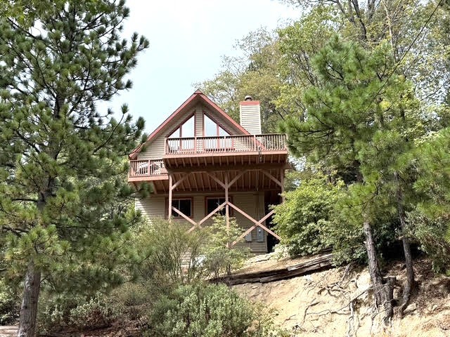 114 Old Toll Rd, Lake Arrowhead, CA 92352 — 3 Beds | 3 Baths | Lake Home
Updated mountain home with lake view and huge ridgeline views. Level entry from the newly paved access road (with additional parking at Old Toll Rd. driveway) leads to a light, bright main level featuring a living room with a wall of glass, gas fireplace, and large view deck. The open, newer kitchen offers updated appliances, including a gas range, stainless dishwasher, refrigerator, and microwave. Two bedrooms and a full hall bath on this main level.
Upstairs is a loft-style primary suite with an ensuite bath and dramatic A-frame windows framing the view. The lower level adds a family room, a large laundry room with bath, and an unfinished workshop/buildup area with extra storage below. The home also includes a newer tankless water heater, mini split AC upstairs and wall AC downstairs, a generator for winter convenience, level entry at access road, and easy neighborhood strolls, close to hiking, shopping, Lake Arrowhead Country Club for a round of golf, and great commuter location. Lake rights included and high-end furnishings are negotiable.