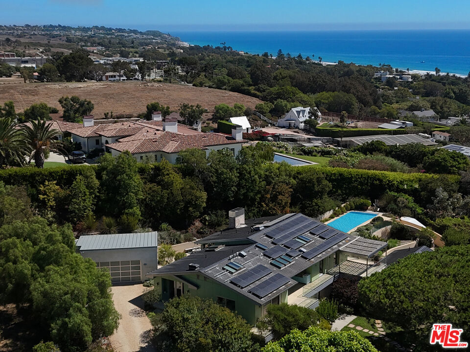 Malibu Retreat on Philip Avenue. Tucked away on approximately one acre with ocean views, this 5,966-square-foot estate combines modern sustainability with timeless California living. Designed for comfort and functionality, the property features a main residence and guest house powered by an advanced solar system with Tesla battery backups, ensuring peace of mind and continuous power, even during extended outages. Interior Highlights- the main level showcases walnut floors, while the lower level is finished in limestone. Expansive bedrooms include large walk-in closets and spa-inspired bathrooms with dual sinks, jacuzzi tubs, and private shower rooms. Automated Lutron lighting, programmable shades, and radiant heating provide both luxury and efficiency throughout. The chef's kitchen is fully equipped with a six-burner Viking gas cooktop, a wok burner, a 30" Viking electric oven, dual dishwashers, multiple refrigerators, and freezers, making it an entertainer's dream. Adjacent, the living spaces feature skylights, electric shades, and seamless indoor-outdoor flow. Exterior & Grounds - Outdoors, a 52-foot heated pool with an electric cover invites year-round enjoyment, complemented by a large Viking BBQ, heated patios, and landscaped vegetable gardens with drip irrigation. A standing seam roof, integrated alarm system, and automated exterior lighting offer durability and security. Guest House - The detached guest house includes its own solar source, electric water heater, radiant heating, and ceiling fans, ensuring complete independence and comfort. Dual laundry rooms, including a garage setup that operates during outages. Custom details include energy-efficient standing seam roofing and a Lutron lighting system. Security lighting is activated by bedside and entryway controls. This Malibu retreat balances modern sustainability with elegant living, making it an ideal sanctuary and just a quick walk to the beach.