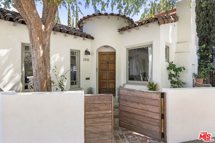 Hidden in the trees on a lush Silver Lake hillside, this 1930 Spanish Bungalow feels like a secret escape, with a turreted entry, arched details, separate guest suite and park-like grounds. The bright living room is anchored by a sculptural hearth, with a formal dining room that frames postcard views of the hills. Wood floors run throughout, and modern updates are smart and subtle. The kitchen delivers ease with stainless appliances, ample counter space, and a breakfast nook that opens to a balcony wrapped in greenery. Two calm, sunlit bedrooms sit upstairs, with a vibey vintage bath finished in emerald tile. The downstairs, an independent suite with a private entrance, includes its own bedroom, bath, kitchen, ideal for hosting or creative use. The backyard feels like your own nature reserve, with a fountain and multiple zones for lounging, dining, or daydreaming under the trees. Amenities include AC, laundry and parking. Just moments from Whole Foods, Broom Street, the Reservoir, and more.