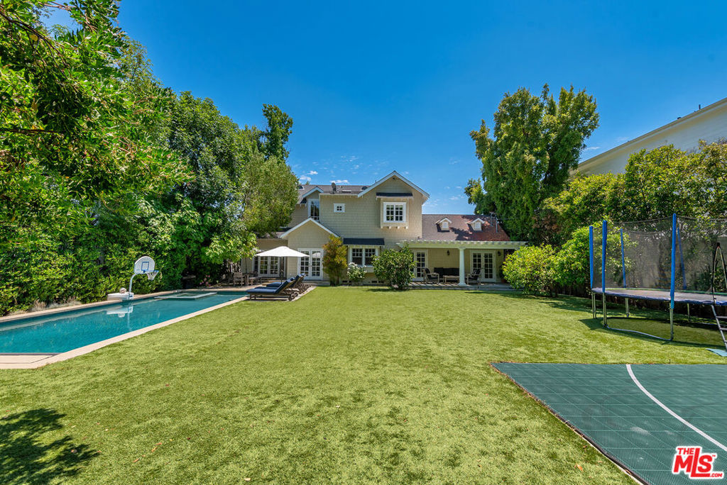 Located at the entrance of Royal Oaks in Encino, this gated Hamptons-style masterpiece with amazing curb appeal and classic elegance is situated on a 12,366 sq. ft. flat lot in the coveted Lanai/Hesby Oaks Jr school district. As you enter the grounds, you immediately feel the privacy and security provided by the fully matured trees that completely surround the property. At almost 3800 sq ft of living space, the home offers 5 bedrooms & 4 bathrooms with an ideal layout for both family living and entertaining. The first floor encompasses a carefully laid out floor plan that flawlessly blends elegance, coziness and functionality, featuring beautiful crown moldings throughout, a formal dining room with wood paneling, a living room with a fireplace, cathedral-ceiling stairwell, including a sun-drenched family room and breakfast room wrapped in French doors leading out to the expansive yard. The gourmet kitchen is a chef's dream, outfitted with a spacious center island, stunning Carrara marble counter tops, custom cabinetry, walk-in pantry & charming breakfast area. The kitchen opens to a large family room anchored with built-in bookshelves and French doors which open to a park-like backyard with large patio & pergola, sparking pool with automatic cover, and sports court. Surrounded by lush hedging, the entire yard feels like a retreat. The primary suite includes soaring ceilings, a spa-inspired bath with dual vanities and a luxurious soaking tub, including a large walk-in closet. The second floor includes three more charming, generously-sized bedrooms and two bathrooms. A full bathroom and fifth bedroom are located on the main level, ideal for guests. Other amenities include: a true sitting front porch, 2-zone HVAC, interior/exterior cameras, and an oversized 2-car garage with an 240V electric vehicle charger. The home is conveniently located walking distance to shopping and dining options on Ventura Blvd, with easy access to the westside of LA.