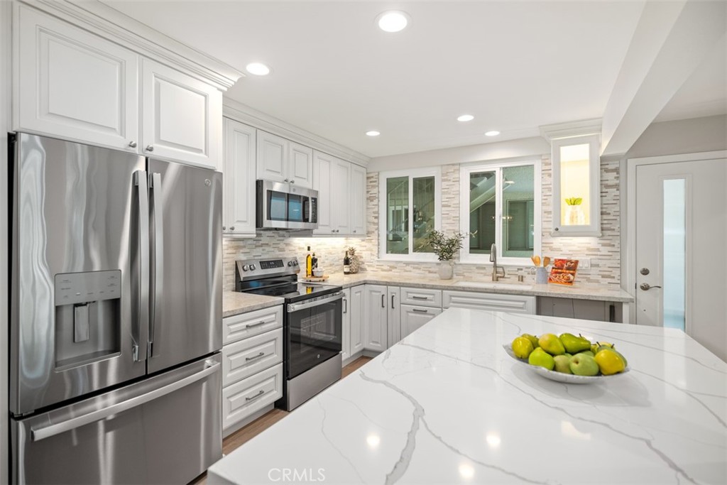 REMODELED & REDESIGNED "Majorca" model MOVE IN READY. Designer, architect and a top Laguna Woods contractor all came together to make this home the most OUTSTANDING ready for you. The sophisticated design features a new open floorplan with gourmet kitchen including ALL NEW STAINLESS appliances, quartz counters, HUGE QUARTZ ISLAND for entertaining, self-closing & soft closing combination of drawers and cabinets to maximize storage & the ease of use. The dining area has an EXPANDED BANK OF CABINETS FOR MORE STORAGE. For even more storage there is a WALK-IN PANTRY. All of this opens up to a "Show Stopping" MEDIA WALL with a 75" flat screen TV & MODERN ELECTRIC FIREPLACE. "Easy Living" sophisticated "wood look" Laminate plank flooring throughout. Main bedroom now features a WALK-IN CLOSET with ENSUITE bathroom REDESIGN has double vanity, high end cabinets and GLASS ENCLOSED "Spa Like" WALK IN SHOWER. Behind the scenes is New ENERGY EFFICENT CENTRAL HEAT & AC & New DUAL PANE WINDOWS for your comfort. NO STAIRS. PRIVATE PATIO off great room overlooks PARK LIKE SETTING with street parking right in FRONT. Inside closet for laundry with stacking unit already installed. All within the premier 55+ community of Laguna Woods with a 27-hole golf course, 9-hole executive par 3 course, tennis courts, pickleball, lawn bowling, 2 fitness centers, 7 clubhouses, 5 pools, equestrian center, garden centers, art studio, etc. Best kept secret less than 10 miles from the coast of Laguna Beach.