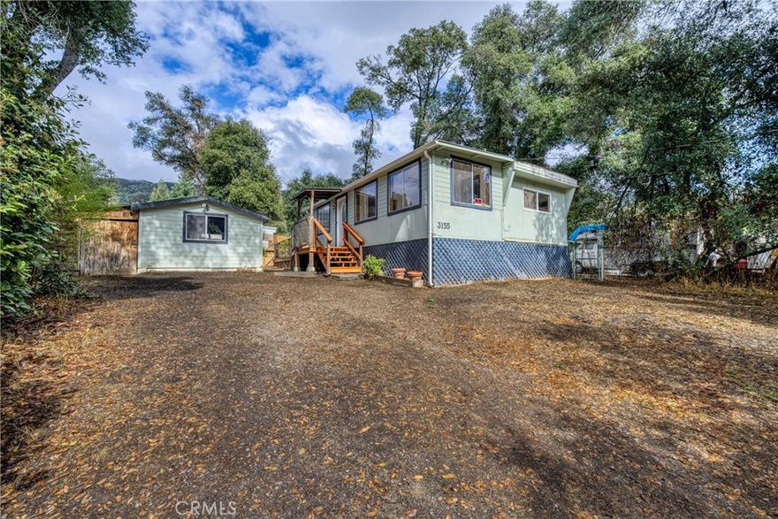 This charming, quiet, and quaint 2-bedroom, 1-bathroom manufactured home offers 1,070 square feet of beautifully updated living space on its own land. Originally built in 1969, the home has been tastefully redone with fresh paint, laminate, and tile flooring throughout. A spacious 10 x 35 addition nearly doubles the original size, creating a large tiled dining area and an expanded living room that's perfect for relaxing or entertaining. The kitchen is adorable and well-appointed with a stove, microwave, dishwasher, kitchen island, ample cupboards, and plenty of storage space. Outside, you'll find a lovely backyard sitting area ideal for enjoying peaceful mornings or quiet evenings. The land itself is a large spacious lot with a park like setting. The home offers two forms of heating: a wood stove and a monitor heater, as well as wall A/C units to keep things cool in the warmer months. Located not far from the lake, this property puts you close to outdoor recreation in every direction—from hiking and biking to all kinds of lake activities. An exterior workshop provides space for all your hobbies, and there's also a shed for garden tools and a woodshed for storing your winter firewood. Owner may carry, truly a must-see.