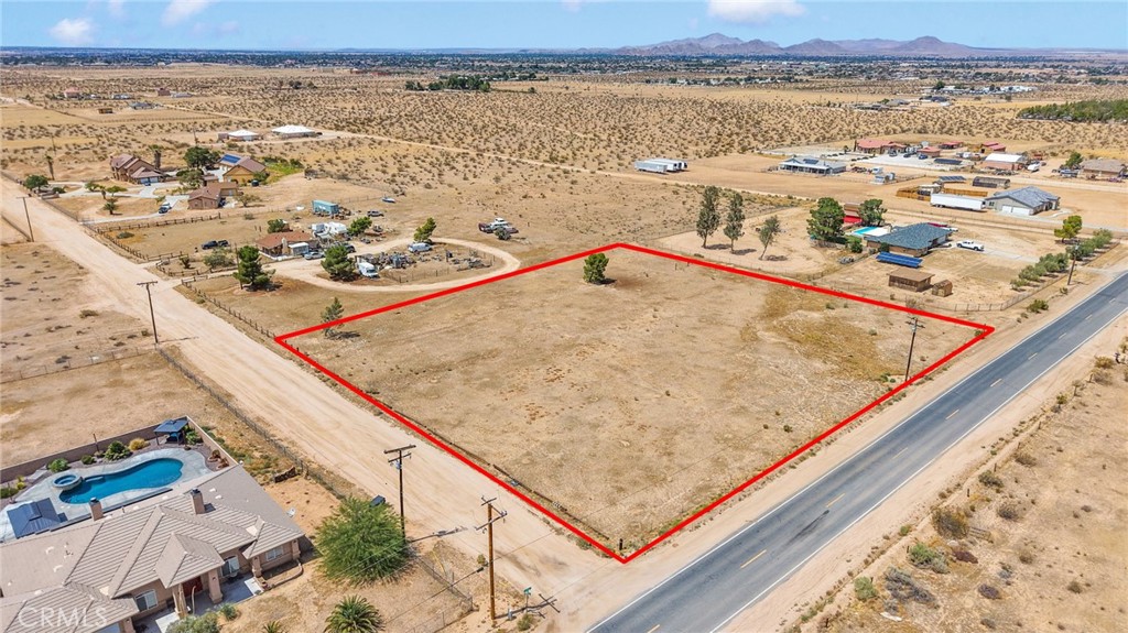 Corner lot on PAVED JOSHUA ROAD in the county area of APPLE VALLEY just off BEAR VALLEY ROAD. This unusual find is a water well area, but has natural gas at the street. Next door home is connected to the gas main. Electric also at the road. This property is listed alone, but the seller has also listed the neighboring house and two lots that sit at the West property line of this large 2.5 ACRE lot: lots 15, 16, 17 listed separately. This property is IDEAL in that it is unincumbered by terrain, vegitation, or access issues. It is FLAT, on a PAVED ROAD, utilities at the road; and once a well is installed, will enjoy free use of water. Imagine having an orchard, horses, livestock, etc. on your very own lot. Gorgeous mountain views. Stores and conveniences just MINUTES from this location. New big box retail is currently under construction just a few miles from this location so the convenience for grocery and retail are only getting better!