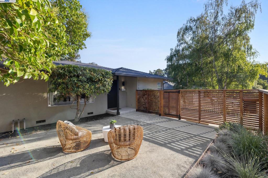 Situated in a peaceful Hayward hillside enclave, this striking Mid-Century Modern residence captures the timeless charm of its era while offering modern-day functionality. Thoughtfully remodeled in 2010, the home is a harmonious blend of clean architectural lines, natural light, and indoor-outdoor living. The main level features a flexible, open layout with two generously sized bedrooms and two full bathrooms. The inviting living room is anchored by a fireplace clad in handcrafted Heath ceramic tile and flows seamlessly into the open-concept kitchen outfitted with warm wood cabinetry and floor-to-ceiling windows that invite the outdoors in. Hardwood flooring runs throughout, adding warmth and elegance. Just a few steps down, a spacious family room offers a perfect space for work, play, or entertaining, with sliding doors that open to a tranquil backyard retreat. The backyard is a true oasis, complete with a relaxing barrel sauna and a concrete carport that offers potential for future development, such as a rooftop deck or additional structure. Upstairs, the expansive primary suite offers the ultimate sanctuary. Vaulted ceilings, a private sitting/media area, a walk-in closet, and a spa-inspired ensuite bath with dual vanities set the tone for comfort.