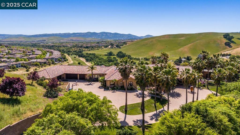 OPEN 8/2 1:30-4:30 Situated in Danville atop a private hill on apx.11.6 sprawling acres, this exceptional custom estate offers a rare blend of refined luxury, architectural distinction & natural beauty. This is not just a home-it's a rare opportunity to own a slice of Danville-for those who seek extraordinary! With apx. 5,843 sq ft, this residence is exquisitely designed w/vaulted ceilings w/wood-wrapped steel beams, expansive walls of glass flooding interiors w/natural light & frame sweeping views of the valley. From nearly every vantage point, enjoy awe-inspiring panoramas-rolling hills by day & sparkling lights by nite. The elevated position ensures both privacy & commanding presence, making it a true sanctuary above it all-create a family compound! The grounds encompass 30 palm trees, infinity pool & spa, BBQ w/built-in table. Multiple courtyards adorned w/3 tranquil fountains, along w/expansive paver entryways create a seamless connection between indoor/outdoor living. From the moment you arrive, the gated property captivates w/its grand motorcourt & 6 car garage. Inside, the home is a showcase of craftsmanship w/a grand great room, gourmet kitchen, bar & aquarium. Owner's suite w/walls of glass, fireplace, heated floors, sauna, skylight.Tesla Walls, Solar & Public Utilities