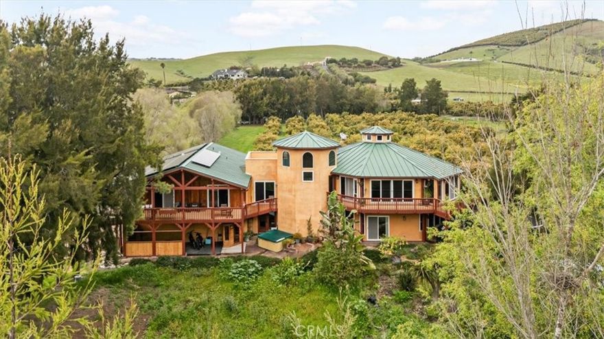 Casa Milagro is a secluded estate in the serene Morro Valley, just outside Morro Bay. This stunning property blends privacy, natural beauty, and functionality, ideal as a family estate, working ranch, agri-tourism business, or vacation rental. Featuring a fully operational avocado grove and Little Morro Creek meandering through the land. Two wells support the property.   The custom-built home spans 4,852 sq,ft, offering 6 bedrooms, 5 1/2 bathrooms, a home office, and multiple living spaces. A 4 car garage with an extended workshop provides ample storage. The estate covers 10.87 acres across two parcels, with a fully irrigated orchard of 425 avocado trees, plus cherimoya, apple, peach, lemon, & lime trees. The multi-level home is designed for comfort & practicality. The first level features a mudroom with a steam shower, a full bath, & a laundry room with stained concrete flooring. Just outside, a hot tub and covered patio offer relaxation, while a retention basin could serve as an herb garden or event space. The second level has a family room with a bar, granite countertops, and cork flooring, plus 2 bedrooms, a bathroom, and a home office. The third level is a self-contained 1,600 Sq.Ft. living space with 3 bedrooms, 2 bathrooms, a full kitchen, a fireplace, and a private 300 Sq.Ft. covered deck overlooking the creek. The fourth level serves as the primary residence, including a grand living area with exposed beams, hardwood floors, and a cupola for natural airflow. The fireplace has wrap-around seating and travertine tile. The open-concept kitchen boasts high-end appliances, granite countertops, & under-counter recycle bins. The master suite features a walk-in closet, a jacuzzi tub, and a walk-in shower. A rooftop sun deck is perfect for stargazing and provides easy access to the solar panels. Energy efficiency is key, with a 13.2 kWh solar system, a 20kW Kohler generator, a 5,000-gallon potable water tank, and a Hague water filtration system. The home has an advanced septic system, 2 electric meters, and  fire sprinklers throughout. Featuring an elevator, 30 & 36in doorways, grab bars in bathrooms, and lever-style door handles. Security includes a SimpliSafe system. This is a rare opportunity to own a luxurious yet practical estate in a picturesque setting. Whether as a retreat, working farm, or investment, this extraordinary home offers an unparalleled living experience.