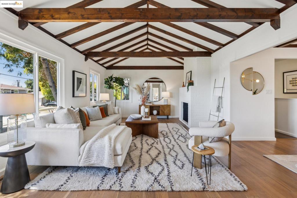 A Redwood Heights wonder, enveloped in lush, mature plantings, this exceptional modern home stuns with rich dark hues and warm wood accents. A bold, custom wood door welcomes you. Inside, a floor-to-ceiling dark wood built-in sets a sophisticated tone, leading to a dramatic living room with exposed beams and expansive windows that flood the room in golden light. From the living room window, take in the San Francisco skyline—truly breathtaking. A charming decorative brick fireplace anchors the room in comfort and timeless character. The seamless flow continues into the dining room—perfectly placed between the kitchen, living room, and outdoor haven. French doors open to a generous deck and terraced gardens that make indoor-outdoor living a daily joy. The updated kitchen features abundant cabinetry, a central prep island, and a sunny eat-in area with direct outdoor access. The backyard is a private retreat: lounge and dining area, flat lush lawn, bountiful green vegetable boxes, a fire-pit gathering, and multiple play zones. Inside, find three serene bedrooms and two beautifully updated baths. Equipped with solar panels, EV charger, central A/C, oversized 2 car garage, and added workshop room, this home blends high-style with modern convenience.Let your heart find its home on Fair!
