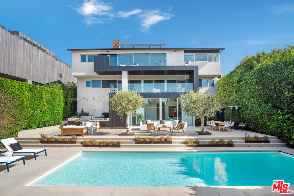This architectural gem is set in one of Santa Monica's most scenic locations. Perched in the hills of the College Streets, on a rare view lot set back from the street, the home offers a serene blend of privacy and luxury in the heart of the Westside. Thoughtfully updated by Space International Architects, this home spans three levels, designed to maximize natural light and frame the expansive ocean, mountain, and city views. A gated entry and lush hedges introduce the property's inviting front yard, complete with a vegetable garden and native Californian landscaping that attract monarch butterflies and hummingbirds. Step inside to discover a welcoming open-concept living space where the kitchen, dining area, and formal living room flow seamlessly. The recently completed chef's kitchen features top-of-the-line appliances and premium finishes, showcasing an ocean view that transforms meal prep into a scenic experience. A balcony with a retractable shade extends from the living and dining area, creating the perfect setting for morning coffee or evening sunsets. The primary suite, located off the main living space, offers tranquil ocean views and a sense of seclusion, thoughtfully separated from the other bedrooms. Descending to the middle level reveals three guest bedrooms, two full bathrooms, a spacious family room, and a dedicated office that comfortably seats four, ideal for homework or remote work. The second ocean-facing balcony on this level invites relaxation and is perfect for outdoor dining, while convenient features such as the laundry room, linen closet, and ample storage provide effortless functionality. On the lowest level, a versatile studio space with a kitchenette and a climate-controlled wine cellar opens to the expansive backyard. Designed by Environmental Landscape Development, this private retreat features a solar-heated pool and spa, fire pit, and built-in BBQ. The hardscape is softened by natural grass and native landscaping, creating an idyllic setting for poolside gatherings. A secure gated side entrance provides guests and vendors with direct backyard access, ensuring convenience and privacy. With its meticulous design, rare combination of modern elegance, privacy, and an exceptional, walkable location within the Santa Monica-Malibu Unified School District, as well as local shops and restaurants, this home represents a truly unique offering in one of the area's most desirable neighborhoods. It is a sanctuary of coastal living, cherished by only two previous owners.