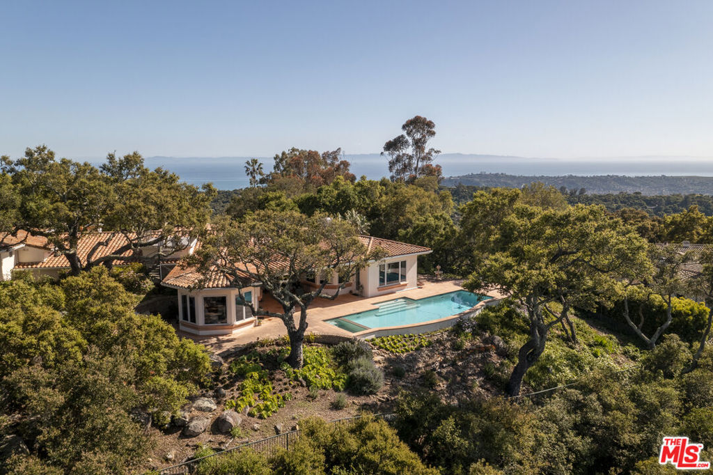 Set on a gated, oak-studded acre with sweeping vistas of the Pacific Ocean, Channel Islands, and Santa Ynez Mountains, this pristine custom-built Santa Barbara Mediterranean estate offers over 5,000 square feet of refined living just minutes from Montecito and the heart of Santa Barbara. Designed & built in 1997 by renowned Westlake Village architect Stephen V. Harrel, the residence was thoughtfully created to frame breathtaking views from nearly every room, while offering a timeless floor plan perfectly suited to today's lifestyle. A light-filled foyer welcomes you into gracious formal living and dining rooms that set the tone for both sophisticated entertaining and everyday comfort.The warm and inviting family room, complete with a fireplace and sunken wet bar, flows seamlessly to the open patio and pool where dramatic mountain views create a stunning backdrop. The kitchen is as functional as it is beautiful, featuring a built-in refrigerator, double ovens, large pantry, ample cabinetry, generous counter space, a breakfast bar, and an inviting dining area framed by awe-inspiring vistas. The expansive primary suite is a private sanctuary, offering a spacious bedroom, an oversized walk-in closet with custom mirrored doors, and a luxurious bath appointed with dual vanities and dual water closets. Additionally, the residence offers a fourth bedroom suite with its own kitchenette, full bath, and private entrance, providing ideal accommodations for guests, extended family, or a quiet home office. This exceptional property is rich in amenities, including a rooftop deck with 360-degree views of the ocean, islands, mountains, and city lights. The outdoor space is designed for entertaining, with a sparkling pool and spa, a generous covered patio, and multiple areas to gather and unwind. An oversized three-car garage with an additional storage room, three-zone heating and air conditioning, a central vacuum system, backup generator, and an elegant paver driveway with ample guest parking complete the home's impressive offerings. Thoughtfully maintained this one-of-a-kind residence presents a rare opportunity to enjoy elevated coastal living in one of Santa Barbara's most scenic locations. This exceptional property is attractively priced and is positioned for immediate consideration.