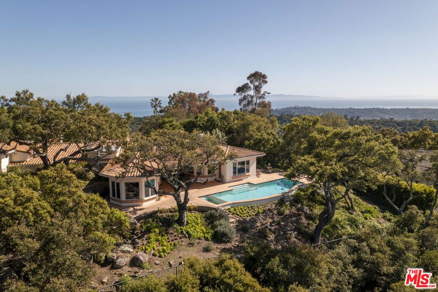 Set on a gated, oak-studded acre with sweeping vistas of the Pacific Ocean, Channel Islands, and Santa Ynez Mountains, this pristine custom-built Santa Barbara Mediterranean estate offers over 5,000 square feet of refined living just minutes from Montecito and the heart of Santa Barbara. Designed & built in 1997 by renowned Westlake Village architect Stephen V. Harrel, the residence was thoughtfully created to frame breathtaking views from nearly every room, while offering a timeless floor plan perfectly suited to today's lifestyle. A light-filled foyer welcomes you into gracious formal living and dining rooms that set the tone for both sophisticated entertaining and everyday comfort.The warm and inviting family room, complete with a fireplace and sunken wet bar, flows seamlessly to the open patio and pool where dramatic mountain views create a stunning backdrop. The kitchen is as functional as it is beautiful, featuring a built-in refrigerator, double ovens, large pantry, ample cabinetry, generous counter space, a breakfast bar, and an inviting dining area framed by awe-inspiring vistas. The expansive primary suite is a private sanctuary, offering a spacious bedroom, an oversized walk-in closet with custom mirrored doors, and a luxurious bath appointed with dual vanities and dual water closets. Additionally, the residence offers a fourth bedroom suite with its own kitchenette, full bath, and private entrance, providing ideal accommodations for guests, extended family, or a quiet home office. This exceptional property is rich in amenities, including a rooftop deck with 360-degree views of the ocean, islands, mountains, and city lights. The outdoor space is designed for entertaining, with a sparkling pool and spa, a generous covered patio, and multiple areas to gather and unwind. An oversized three-car garage with an additional storage room, three-zone heating and air conditioning, a central vacuum system, backup generator, and an elegant paver driveway with ample guest parking complete the home's impressive offerings. Thoughtfully maintained this one-of-a-kind residence presents a rare opportunity to enjoy elevated coastal living in one of Santa Barbara's most scenic locations. This exceptional property is attractively priced and is positioned for immediate consideration.