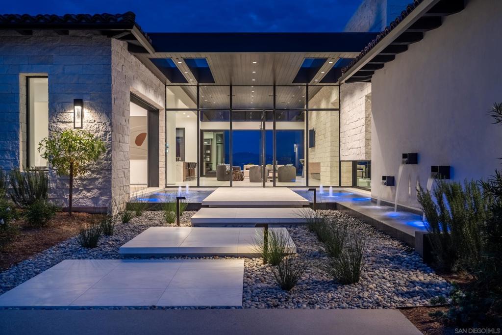 Presenting an extraordinary, spectacularly customized 5+ bedroom modern estate built in 2020, situated on the desirable West Side of Rancho Santa Fe Covenant. Not a single step in this house, this home exudes opulence from every corner, showcasing chic contemporary styling infused with elegant Italian influences. As you enter through the pivot entry door, your gaze is immediately drawn to the breathtaking views through the walls of glass, which overlook a magnificent zero-edge radius pool. The kitchen is a culinary masterpiece, boasting top-of-the-line Miele appliances and a Sub-Zero fridge/freezer. Adjacent to the kitchen, the great room is a sight to behold, featuring soaring 14' ceilings adorned with intricate wood detailing. The room is further enhanced by a custom, crafted fireplace known as the Floating Fire Tray, the largest in all of San Diego. Prepare to be captivated by the Primary Suite, where exquisite details abound. An automated pocket door grants access to this private oasis, where an LED-lit drop ceiling and a stunning slab-covered fireplace create an ambiance of indulgence. The primary spa bath is a haven of relaxation, complete with Fantini fixtures, stone slab walls, and automated window shades. The custom couture Italian Made closet is a testament to elegance, meticulously designed after the fashion boutiques of Milan, featuring custom Italian cabinetry and several glass LED display cases. This home boasts unique design elements that set it apart from all others. The kitchen is a culinary masterpiece, boasting top-of-the-line Miele appliances and a Sub-Zero fridge/freezer. Adjacent to the kitchen, the great room is a sight to behold, featuring soaring 14' ceilings adorned with intricate wood detailing. The room is further enhanced by a custom, crafted fireplace known as the Floating Fire Tray, the largest in all of San Diego. Prepare to be captivated by the Primary Suite, where exquisite details abound. An automated pocket door grants access to this private oasis, where an LED-lit drop ceiling and a stunning slab-covered fireplace create an ambiance of indulgence. The primary spa bath is a haven of relaxation, complete with Fantini fixtures, stone slab walls, and automated window shades. The custom couture Italian Made closet is a testament to elegance, meticulously designed after the fashion boutiques of Milan, featuring custom Italian cabinetry and several glass LED display cases. This home boasts unique design elements that set it apart from all others. The Game Room provides an unparalleled vantage point with its cornering glass walls, offering panoramic views. The Office features a striking floor-to-ceiling glass wall design, while the powder bath is flooded with natural light streaming from a skylight positioned 12 feet above, complemented by a custom black slab sink. Additional highlights of this extraordinary property include a detached Guest House spanning 1,000 sq.ft., a convenient in-home gym, cutting-edge SMART-home technology, and a prime location that epitomizes exclusivity. Welcome to a life of unrivaled luxury.