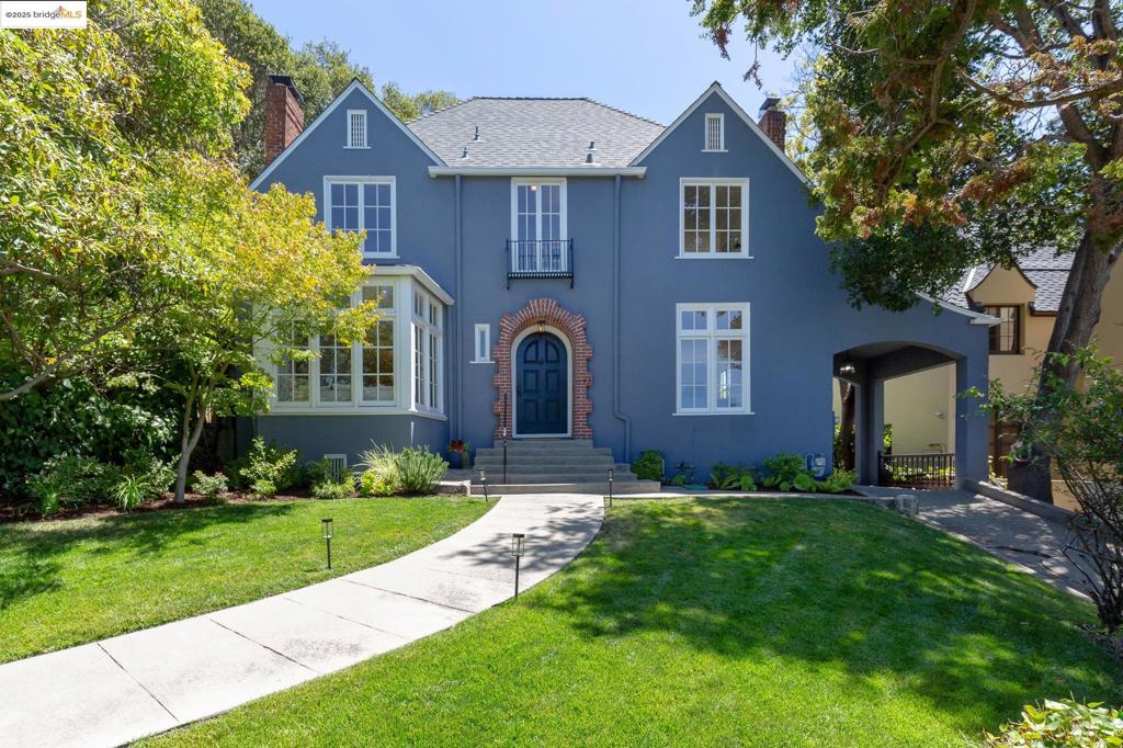 Rumored to have been built by a bank president for his opera-singer wife, this captivating home blends romantic history with timeless architecture. Perched above the street, 1145 Mandana enchants with a dramatic entry, meandering gardens, natural light, and period charm. The main level features a cozy sitting room with fireplace and skyline views, a formal living room with coved ceilings, built-ins, and a second fireplace, plus an elegant dining room. The kitchen with center island, farmhouse sink, and Wolf range includes French doors that open to the expansive backyard. A main-level bedroom with en-suite bath offers flexibility for guests, family fun and homework. Upstairs are two large bedrooms, a shared bath, and a sunlit bonus room off the primary with access to a rear terrace. This can function as a nursery or office. The meandering rear grounds offer a level lawn for play, a variety of planting beds, a prolific pear tree and the space for dining, entertaining and lounging. A detached garage fits naturally into the landscape and has been partially converted into a studio, perfect for a hobby space, gym or office. Just over a mile to Lakeshore shops and dining, with easy access to Lake Merritt, transit, and freeways, be prepared to fall in love.