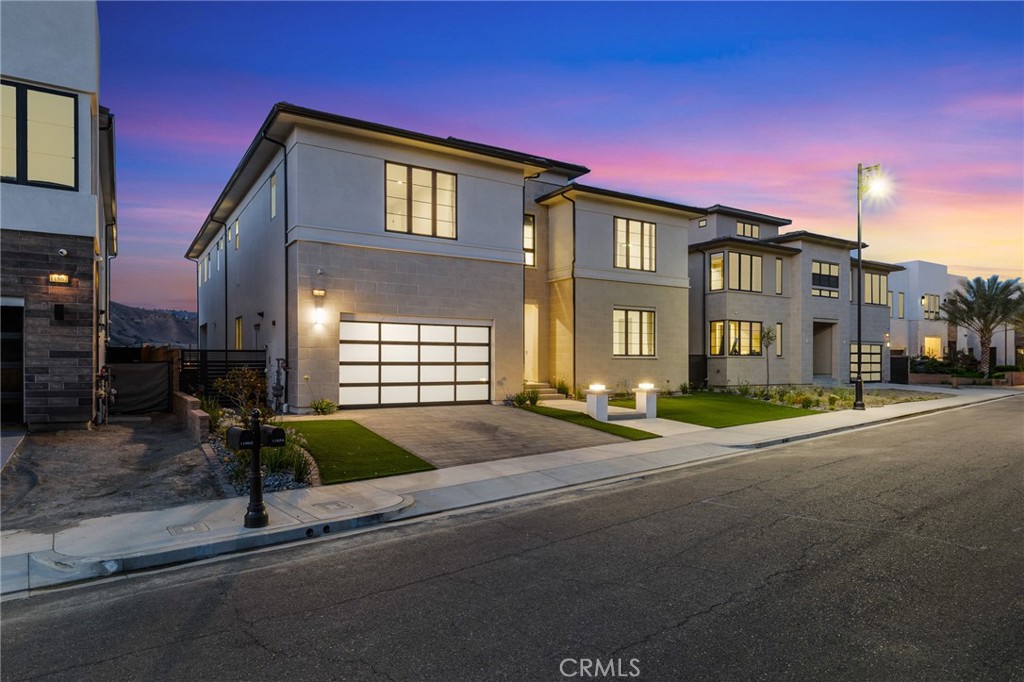 Welcome to this architecturally striking residence built in 2024, located in the exclusive gated community of Westcliffe at Porter Ranch. This contemporary showpiece boasts 5 bedrooms, 6 bathrooms, and offers just over 4,700 square feet of meticulously designed living space on a sprawling 10,700 square foot lot.As you approach, the stunning curb appeal immediately commands attention with its clean lines, smooth stucco finish, and frosted glass garage doors. Step inside to a world of elevated elegance and cutting-edge design.The grand entry opens to a floating modern staircase with sleek glass railings and matte black steps that complement the high ceilings and expansive sightlines. Soaring two-story ceilings in the great room are framed by massive floor-to-ceiling windows that flood the space with natural light, while an oversized linear fireplace adds warmth and sophistication. Motorized sliding doors seamlessly connect the indoor living space to a private outdoor oasis.At the heart of the home lies the designer kitchen, outfitted with top-of-the-line Wolf and Sub-Zero appliances, dual ovens, a massive waterfall-edge quartz island, and flat-panel custom cabinetry with matte black hardware. The stunning chevron-patterned tile backsplash adds texture and flair, while under-cabinet lighting and a matte black commercial-style faucet complete the ultra-modern aesthetic.Upstairs, a spacious loft-style bonus room with glass overlook offers a flexible space perfect for a second family room, game area, or creative retreat. Plush carpet and recessed lighting make this upper-level sanctuary both cozy and contemporary. The backyard is a true entertainer’s dream, featuring custom hardscaping, low-maintenance turf, and a professionally installed putting green—all set against the backdrop of Porter Ranch’s rolling hills and open skies. Enjoy indoor-outdoor living at its finest with covered patios, sleek landscaping, and ample space to add a pool or outdoor kitchen. This home is nestled in a secure, upscale enclave just minutes from The Vineyards at Porter Ranch, top-rated schools, scenic trails, and convenient freeway access. Whether you’re hosting guests, raising a family, or simply enjoying the best of California living. Please Reach out for a private showing.