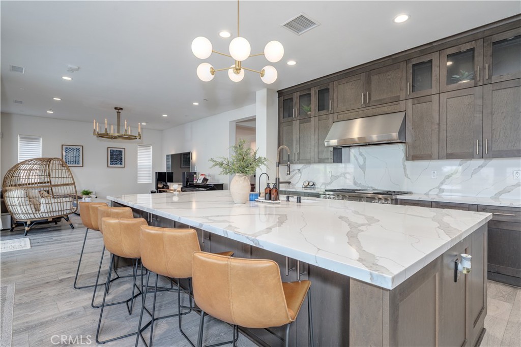 Welcome to the pinnacle of luxury coastal living in Parkside Estates, one of Huntington Beach’s most exclusive and sought-after communities. Nestled in this idyllic neighborhood, you will find a breathtaking 5-bedroom, 5.5-bathroom residence spanning over 4,100 square feet, making it the largest model available in the community. This impressive home features a well-appointed main level, complete with 1 bedroom, 1.5 bathrooms, and an inviting office space. Step into the heart of the home—the incredible chef's kitchen—where culinary dreams come to life. It is equipped with top-of-the-line Wolf appliances, a built-in Pro Style microwave, a state-of-the-art Sub-Zero refrigerator, and a stylish Monogram wine chiller, making it perfect for hosting unforgettable gatherings. The expansive island, with elegant under-counter cabinet storage, provides generous workspace, while the walk-in pantry and butler’s pantry offer additional organization and convenience. As you ascend to the upper level, you will discover the primary suite, a sanctuary of tranquility featuring a spacious, custom-built walk-in closet designed for both practicality and luxury. One of the bedrooms has been beautifully transformed into the ultimate 13 X 11.5-foot designer closet, which can easily be converted back to a bedroom. This space elegantly showcases your most treasured garments and accessories. Each bathroom throughout the home showcases exquisite builder upgrades, enhancing the sleek aesthetic with brushed nickel framing, polished-edge mirrors, and radiant interior LED lighting. Designer light fixtures, tasteful wood shutters, elegant Hunter Douglas Silhouette blinds, designer carpeting, and modern wallpaper accents add layers of sophistication and warmth. Venture outside to the outdoor space, where you will find a Coastal California Room complete with a fireplace, creating the perfect ambiance for year-round relaxation. The sleek deck and green areas invite you to indulge in al fresco dining while enjoying the soothing ocean breeze. The community itself is a true oasis, featuring 20 acres of verdant open space and a dedicated wildlife habitat preservation area. Enjoy picturesque walking trails that meander through coastal wetlands, leading you to the sands of Bolsa Chica State Beach. The neighborhood park, playground, and picnic area add to the charm of the neighborhood. This extraordinary residence offers unparalleled access to Southern California’s enviable coastal lifestyle.