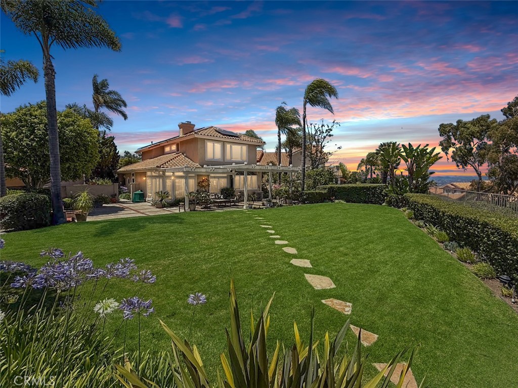 Perfectly positioned on a quiet cul-de-sac in the prestigious and highly desirable Village Niguel Summit community, this charming Mediterranean-style home offers luxury living with breathtaking panoramic views of the coastline, city lights, Saddleback Mountain, and Mt. Baldy. Inside, cathedral ceilings and a bright open floor plan create a warm, welcoming atmosphere enhanced by travertine flooring, with the exception of the carpeted living room. The second level is wood with ceramic tiles in the bathroom. The remodeled kitchen showcasing custom Alderwood cabinetry, granite and stone countertops, and soft-close drawers, perfectly opens to a spacious family room with a cozy fireplace. The primary suite offers a tranquil retreat, complemented by a remodeled en-suite bathroom featuring dual vanities and a walk-in shower with dual shower heads. Additional updated bathrooms include Toto low-flow toilets. Functionality meets thoughtful design with attic storage and a collapsible ladder, custom garage cabinetry with a utility sink and stone countertops, and added under-stair storage for smart organization. This exceptional home is loaded with premium upgrades, including fully paid-for solar, a brand-new 2024 HVAC heat pump with an Aprilaire air filtration system, and Ecobee smart thermostats for optimal energy efficiency. All windows have been upgraded to high-performance Milgard models, ensuring comfort and insulation year-round. The home is equipped with exterior security cameras and motion-sensor lighting, offering enhanced safety and peace of mind. A very special feature of this home is it has been designated as a Certified Wildlife Habitat by the National Wildlife Federation landscaped to support local birds, butterflies and pollinators with natural food, water and shelter sources. Retreat to the backyard oasis featuring a fire pit with seating perfect for entertaining or enjoying the surrounding natural beauty. Situated on one of the largest non–zero lot line yards in the community, the expansive yard has custom low-voltage landscape lighting, perfect for both privacy and outdoor entertaining. With low HOA dues, world-class views, and a list of high-end upgrades, don’t miss this opportunity to own a premier property in the heart of Laguna Niguel.