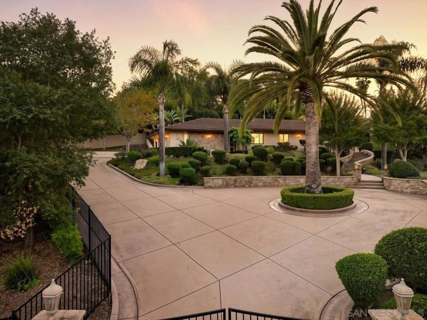Welcome to a sanctuary of sophistication in West Escondido. This gated estate blends timeless design with modern luxury, offering a lifestyle of serenity, beauty, and effortless entertaining. From the moment you arrive, the circular driveway and lush gardens set a gracious tone. Beveled glass doors open to a sunlit interior where vaulted ceilings and travertine floors lead to a living room anchored by a dramatic stone fireplace and panoramic views of nature. Designed for gatherings, and fun... See Supplement  A circular drive leads to a stunning entry framed by lush landscaping and beveled glass doors. Inside, vaulted ceilings, travertine floors, and a dramatic stone fireplace define the living room. The formal dining room opens to the pool via folding glass doors and features custom built-ins. The kitchen includes a butcher block island, Miele coffee station, breakfast nook, pantry, and pass-through window to the patio. Adjacent is a spacious laundry room with ample cabinetry. The home offers 5 bedrooms, including a luxurious owner’s suite with walk-in closet, spa-like bath, and an attached office with built-ins.  Outdoor amenities include a 38’ lap pool, raised spa, fire-and-ice features, private cabana, putting green with sand trap, and a 23x19 ft gazebo with granite counters, BBQ, heaters, fans, and TV. Fruit trees, rose garden, scenic walkway, and night lighting complete the resort-style grounds. Epoxy-floored garage with LED lighting and storage. A rare opportunity for refined living.  The kitchen is both warm and functional, with a butcher block island, Miele coffee station, breakfast nook, and pass-through window to the patio. A spacious laundry room adds everyday ease. The owner’s suite is a retreat unto itself, with a spa-inspired bath, walk-in closet, and an adjoining office with granite counters and built-ins. Three additional bedrooms offer comfort and privacy. Outside, the grounds unfold like a private resort: lap pool, raised spa, fire-and-ice features, putting green, cabana, and a fully equipped gazebo with scenic walkway. Fruit trees, a rose garden, and curated lighting complete the ambiance. This is more than a home—it’s a destination.