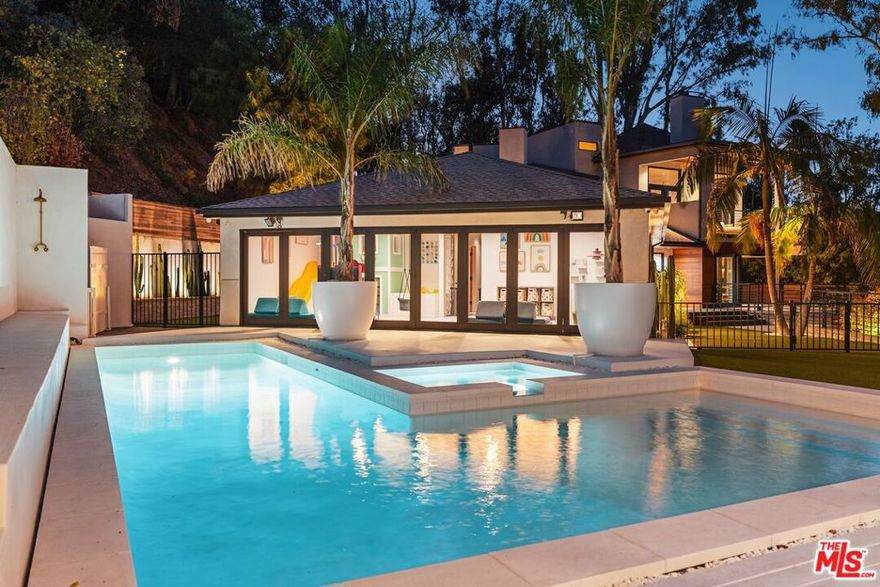 Nestled in the tranquil hills of Studio City, this 5-bedroom, 6-bath residence offers privacy, abundant natural light, and canyon views. Walls of glass and folding doors create a seamless indoor-outdoor flow throughout the expansive living spaces. The interiors combine warm wood accents, sleek black finishes, and polished concrete floors balanced by a soft, neutral color palette.The upstairs primary suite is a retreat of its own, highlighted by soaring ceilings, a stone fireplace, private viewing balcony, and spa-like bathroom with dual vanities, a jacuzzi tub, walk-in shower, and skylight. Secondary bedrooms are generously sized, while a versatile lounge/library provides an ideal bonus space.Outdoor living is elevated by wraparound decks, multiple seating areas, and terraced pathways that lead to a hillside retreat and lookout point. Peaceful yet accessible, this property is just minutes from Ventura Blvd's shops and restaurants, with convenient routes to the Westside and beyond.