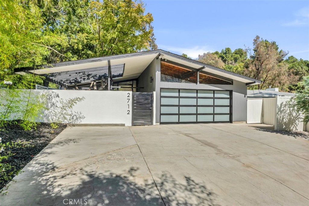Designed by renowned architect Bill Mack—celebrated for his mid-century modern homes in Beverly Glen—this stylish 4 bed, 3 bath Bel Air residence offers a seamless blend of iconic design & modern upgrades. A gated front courtyard welcomes you with low-maintenance landscaping, hardscape walk paths, & open pergola cover, creating a tranquil introduction to the spacious, light-filled interior. A striking floor-to-ceiling glass door opens to soaring ceilings, skylights, & recessed lighting throughout, leading to the open-concept living space with built-in sound speakers. The living room features a custom buildout with TV niche & sleek electric fireplace & direct access to the side yard, while the dining area boasts floor-to-ceiling windows & opens directly to a fully refreshed backyard. Chef-inspired kitchen includes a massive quartz waterfall island with bar seating, updated stainless-steel appliances (double wall convection oven, built-in microwave, & dishwasher), 6-burner cooktop & rangehood, soft-close cabinetry, & a pullout trash cabinet. Included in the 4 bedrooms are 2 spacious primary suites. The front suite enjoys views & access to the private courtyard & features an en-suite with soaking tub, glass-enclosed shower, & generous built-in closet/storage space. The main suite offers a wall-to-wall wardrobe with built-in TV niche, large windows with backyard views, & en-suite with dual vanities, modern soaking tub & expansive walk-in double shower. A passthrough laundry closet connects to a secondary bedroom via pocket doors, while the 4th bedroom is situated adjacent to a full guest bath. Upgrades include natural hickory wood floors, newer roof (2024), updated furnace (2022), new exterior paint, a Tesla charging station, & updated sewer drains to the street. The completely reimagined backyard is a private oasis with sleek heated pool & spa featuring a baja shelf, motorized safety cover, updated pool pump & heater (2021), & wraparound concrete patio with gas line for BBQ hookup. Artificial turf lawn offers room to play & is accented by a raised garden with olive trees—all enclosed by tall privacy walls and backs to quiet, city-owned land with mature foliage & tropical trees. An oversized 2-car garage offers ample storage. Excellent location within the school district of highly rated Roscomare Elementary, & University High, with easy access Beverly Glen’s charming shops & dining options, hiking trails, & minutes to major Westside & Valley destinations.