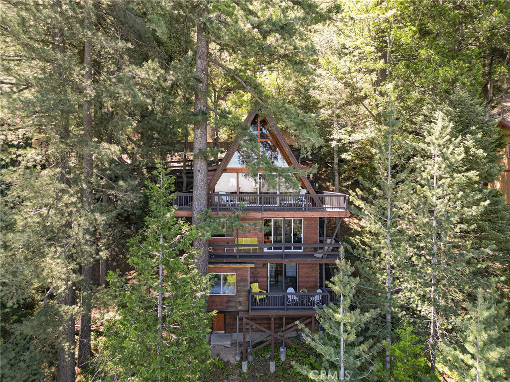 Imagine an impeccably maintained mid-century A-frame cabin, on the market for only the second time in 60 years, with breathtaking jetliner views of the high desert and surrounding mountains: all set on over 1/4 acre of land. Built in 1964 and perched on a mountainside along one of Crestline's most desirable streets, this architectural gem spans five unique levels and sits on three private, view-filled lots. The fully furnished home blends timeless design with modern comfort, featuring solid oak flooring on the main level, original pine floors in the loft, and a custom kitchen and bathrooms adorned with porcelain tile. A flowing floor plan opens onto multiple outdoor living spaces, including a stunning wraparound deck ideal for sunset views, spacious patios and terraces, and a private hot tub nestled among towering pines and natural rock outcroppings. The property also includes a self-contained one-bedroom apartment with its own entrance, making it perfect for multigenerational living or income potential—it currently operates as a successful, county-permitted short-term rental. Additional amenities include a wheelchair-accessible entry and living areas, multiple indoor and outdoor gathering areas and three off-street parking spots. Whether you're seeking a peaceful mountain retreat, a profitable investment, or both, this A-frame offers a rare opportunity just 90 minutes from Los Angeles.