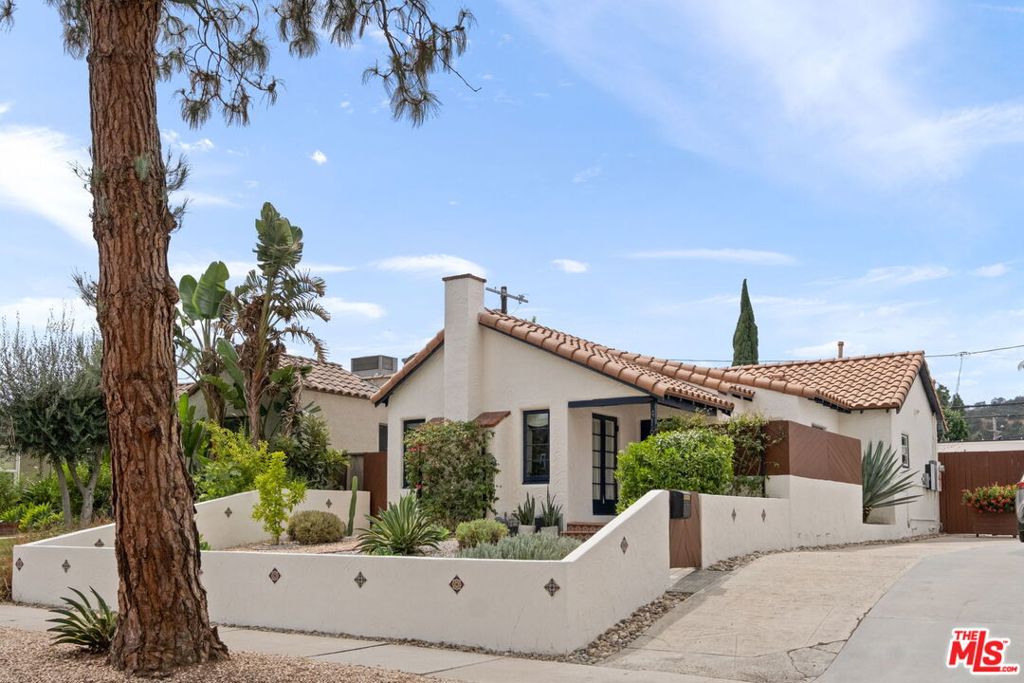 Welcome home to this designer-driven Spanish gem on tree-lined Edenhurst Avenue in the heart of beloved Atwater Village. Perched above the street and set back for privacy, this thoughtfully redesigned home captures you instantly. A lush mix of mature, drought-tolerant landscaping frames the tiled pathway that leads to a private, enclosed front porch complete with custom wooden benches made for morning coffee, quiet reading, or simply soaking in the calm. Open the wooden door and into a large, open-concept floor plan where rich hardwood floors, abundant natural light, and soaring pitched ceilings with exposed beams create a warm, character-filled environment. Sit back and relax in your cozy living room and warm up to your own fireplace, the perfect spot for relaxation. The chef's kitchen blends style and function with quartz countertops, custom cabinetry, high-end stainless-steel appliances, a farmhouse sink, and stackable washer/dryer. The primary feels like a retreat, offering a walk-in closet with custom wood shelving and cabinetry, plus a catalogue-worthy ensuite bath featuring dual sinks, glass-enclosed shower, sliding barn door, and top-tier finishes. An additional bedroom with generous storage, along with a versatile bonus room, is ideal as a sunroom, home office, gym, or guest space and provides plenty of functionality. Step outside to your private backyard oasis, designed for easy LA-living, entertaining and al fresco dining. Enjoy secluded tiled patio with built-in stainless-steel BBQ, while curated potted greenery and privacy fencing create a serene, low-maintenance escape with the City. Detached garage offers endless creative potential whether as a home office, creative studio, or guest space while Tesla solar panels and a tankless water heater installed drip irrigation make it chic, green and sustainable. Just mere moments from the best of Atwater Village: Los Feliz and Glendale Boulevard dining and shops, the LA River walking path, and the vibrant Sunday farmers market. This is the home you've been waiting for where you can truly live the California Dream...