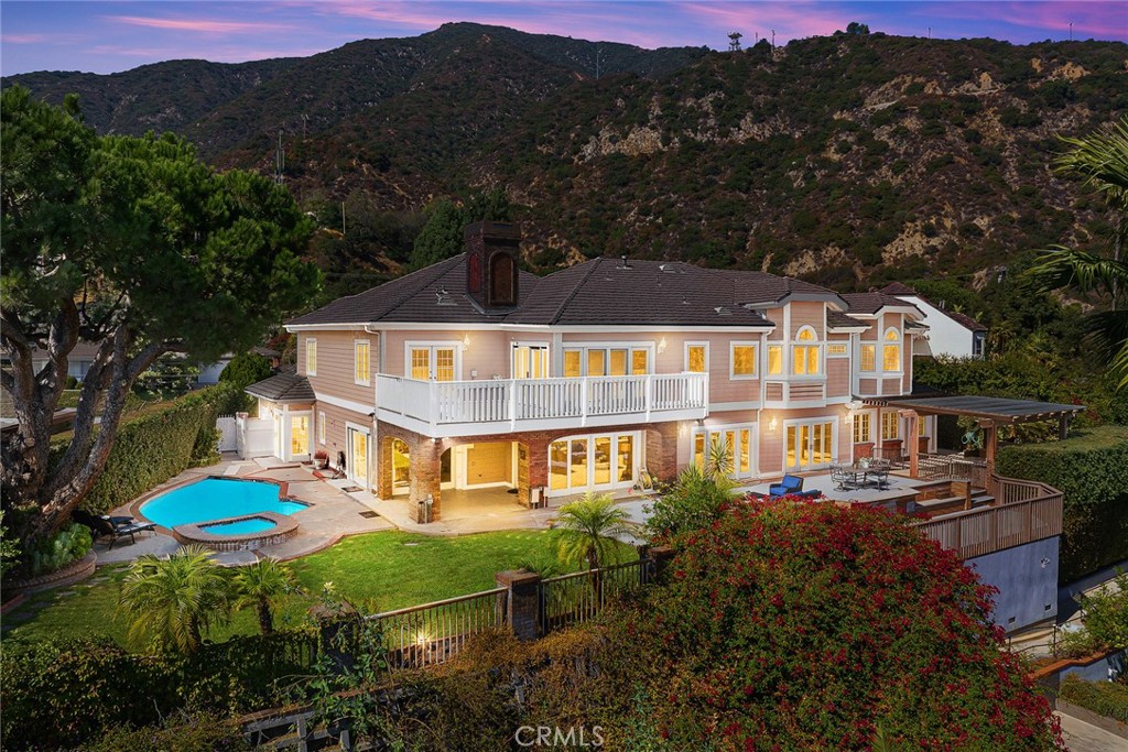 This spectacular view home, nestled in Arcadia's highly desirable Highland Oaks neighborhood, is part of the prestigious Arcadia School District and exemplifies Southern California living with expansive panoramic views of the gardens, mountains and city lights. Situated on a hilltop, this beautifully updated estate offers the perfect combination of serenity, breathtaking views and privacy. As you approach the home you're welcomed by a meticulously landscaped front yard and a paved circular driveway leading to an elegant entry. The artistry of marble inlay flooring graces the entry and living room, which seamlessly integrates indoor and outdoor spaces through walls of glass windows framing the stunning landscapes. The bright family room, with views of the pool and canyon, opens onto a large outdoor patio, perfect for entertaining. Anchored by two gas fireplaces, one in the living room and another in the family room, this home exudes warmth and comfort. The formal dining room and breakfast room, both featuring walls of glass, continue showcasing gorgeous scenic canyon views. Additional features include a large recreation room and beautiful wood floors throughout the living areas, enhancing the home's natural charm. Originally built in 1959 then rebuilt in 1991, this expansive 6,103 sq. ft. estate offers 8 bedrooms, 7.5 bathrooms, with 5 en-suite bedrooms upstairs and 1 en-suite downstairs. The primary suite elevates luxury with a fireplace, direct access to a sun-deck patio, two large walk-in closets, and a spa-like bathroom with a soaking tub offering incredible canyon views. The home is thoughtfully designed for entertaining and enjoying the surrounding garden and pool. Details like crown moldings, recessed lighting, elegant granite finishes, vaulted ceilings in the foyer and well-placed windows capturing sweeping views to include the surrounding beauty as part of the home’s interior demonstrate the attention to detail and design throughout the estate. The professionally landscaped backyard is an entertainer's dream, featuring two covered patios, a fully-equipped outdoor BBQ kitchen, ample decking, a lush lawn, and an inviting pool and spa. This tranquil outdoor space is perfect for leisurely afternoons, gardening, or simply enjoying the beauty of nature in a serene setting. This home truly epitomizes sophisticated California indoor/outdoor living. Be sure to take your time exploring this hilltop gem, a true retreat from the everyday hustle and bustle.
