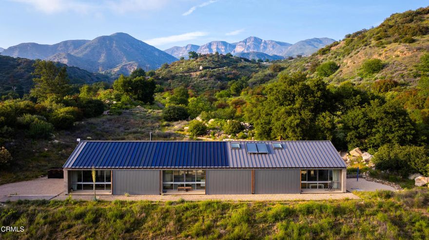 This remarkable forty-four-acre property is set just beneath the Topatopas in Upper Ojai's rugged backcountry where the architect owners designed a modern, sustainable, residential compound. Over the last sixteen years they have rewilded the landscape and developed the walking trails that now vein its chaparral, oak meadowland, sage scrub and riparian habitats. Approached from the South, the compound is entirely hidden from the road. The house, guest house, pool & terraces are enfolded in the crook of a dramatic eastern ridge that provides unparalleled privacy, yet affords views of the Santa Ynez Mountains, the Upper Ojai Valley and Sulphur Mountain Ridge. The property is situated half-way between Ojai and Santa Paula.Surrounded by its gravel precinct, the light-filled, minimalist house sits amidst the trees and shrubs of the chaparral and includes three bedrooms and two baths. The cathedral ceilinged living, dining & kitchen flow into one another flanked by broad passageways and bookended by towering walls that demark the functions. To the North, the house opens to a 12' X 48' pool with views of the Topatopa foothills and beyond, to the mountain's iconic spalled face.Mindful of the heat of summer, the house features shallow covered porches, or loggias, which open to the north and south & provide full summer shade and welcome winter sun. These loggias can be closed behind steel barn doors when there is the threat of wildfire. When not in use they park against the solid stucco walls of the house.The guesthouse/studio and a two-car garage sit below the last curve of the driveway which sweeps up to the house. Its linear design echoes the building above and provides two airy studios linked by an entry hall, a 3/4 bath and an efficiency kitchen.The property comprises two 20+ acre parcels separated by a low ridge dotted with native walnuts, oaks, toyon, and Matilija poppies. The western parcel is bordered by the year-round Bear Creek. Its meadows rise gently to a magnificent oak grove and offer opportunities for both architectural and agricultural development. The residential compound is carefully integrated within a landscape that nurtures the local fauna, birds, bees, hummingbirds and pollinating butterflies, while its buildings are holistically designed to provide serenity, utility & sustainability.Recently certified by Ojai Valley Land Conservancy's 'Rewild Ojai' initiative, the estate was featured on their 2025 Native Garden tour.