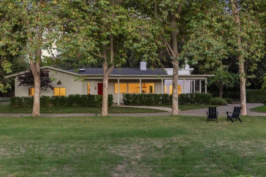 Nestled just two miles from Carmel, this property offers a serene escape on 1.8 acres of lush landscape. Surrounded by the soothing sounds of the Carmel River and whispers of the leaves this haven reveals a charming residence with expansive lawns and vistas. The single-story main home features a beautifully appointed three-bedroom, two-and-a-half-bath layout with light-filled spaces and an inviting eat-in kitchen. A stone fireplace, custom bookshelves, and refinished oak floors are enhanced by a skylight that illuminates marble counters and high-end appliances. With ample windows and doors leading outside, the living area extends to outdoor spaces, ideal for entertaining. The primary suite, a tranquil retreat, features a bay window overlooking a private fenced yard and deck. The spacious bath offers a spa-like experience with granite and stone finishes. A standalone one-bedroom, one bath guest house provides versatile space for guests or an office. Enjoy breathtaking southwest mountain views, framed by lawns and olive trees. The grounds include a two-stall barn with paddocks, a workshop, and a tack room. The property is supported by its own irrigation well and CalAm water service. This is more than a home; it's a place to celebrate life in Carmel Valley with friends and family.